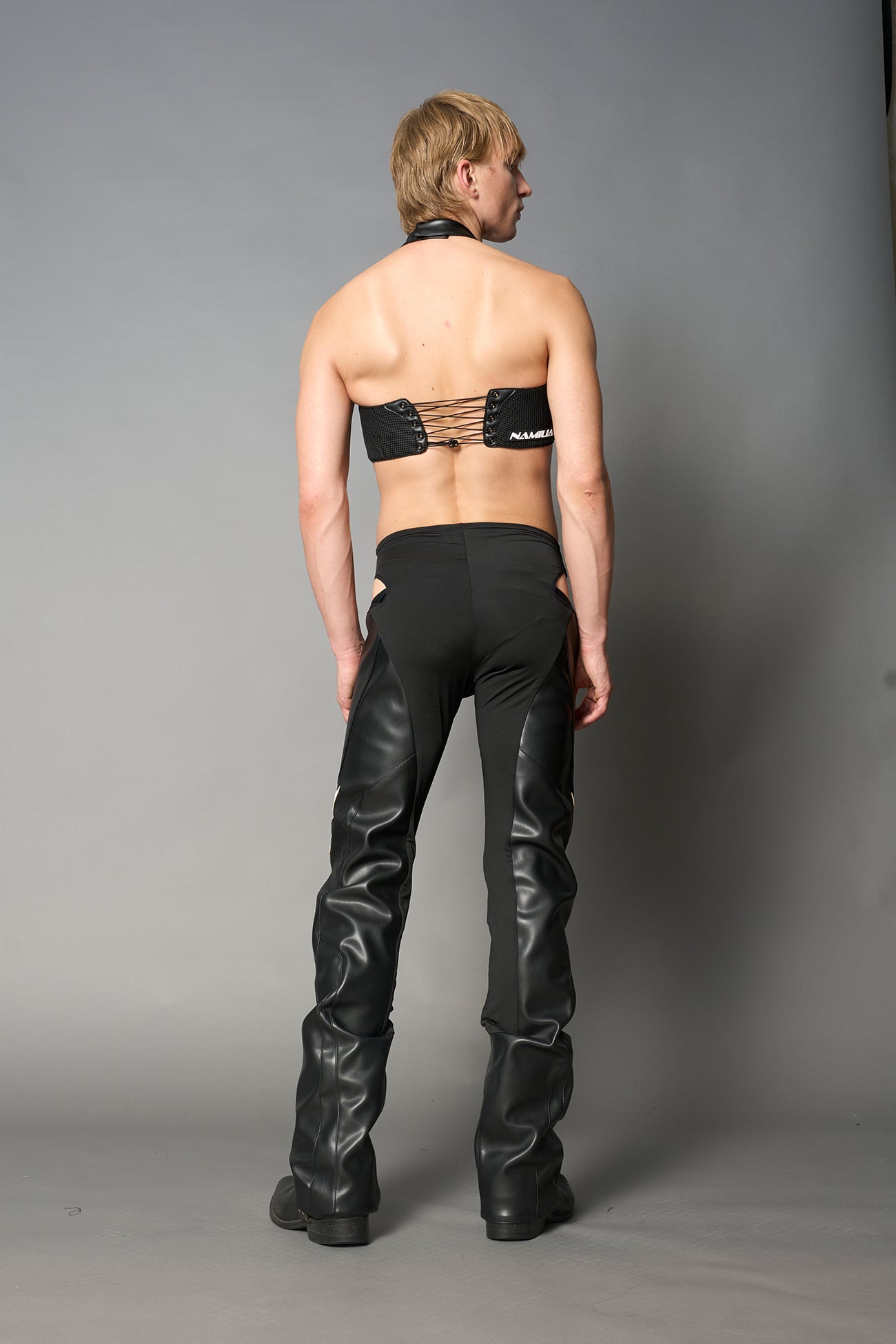 white cut-out flare pants with graphic details, vegan leather panels, and low-rise waist – edgy motocross-inspired trousers for men’s streetwear or festival looks.