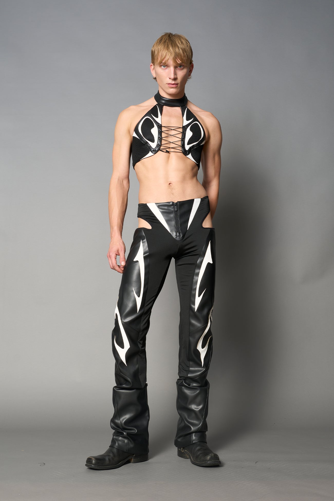 white cut-out flare pants with graphic details, vegan leather panels, and low-rise waist – edgy motocross-inspired trousers for men’s streetwear or festival looks.
