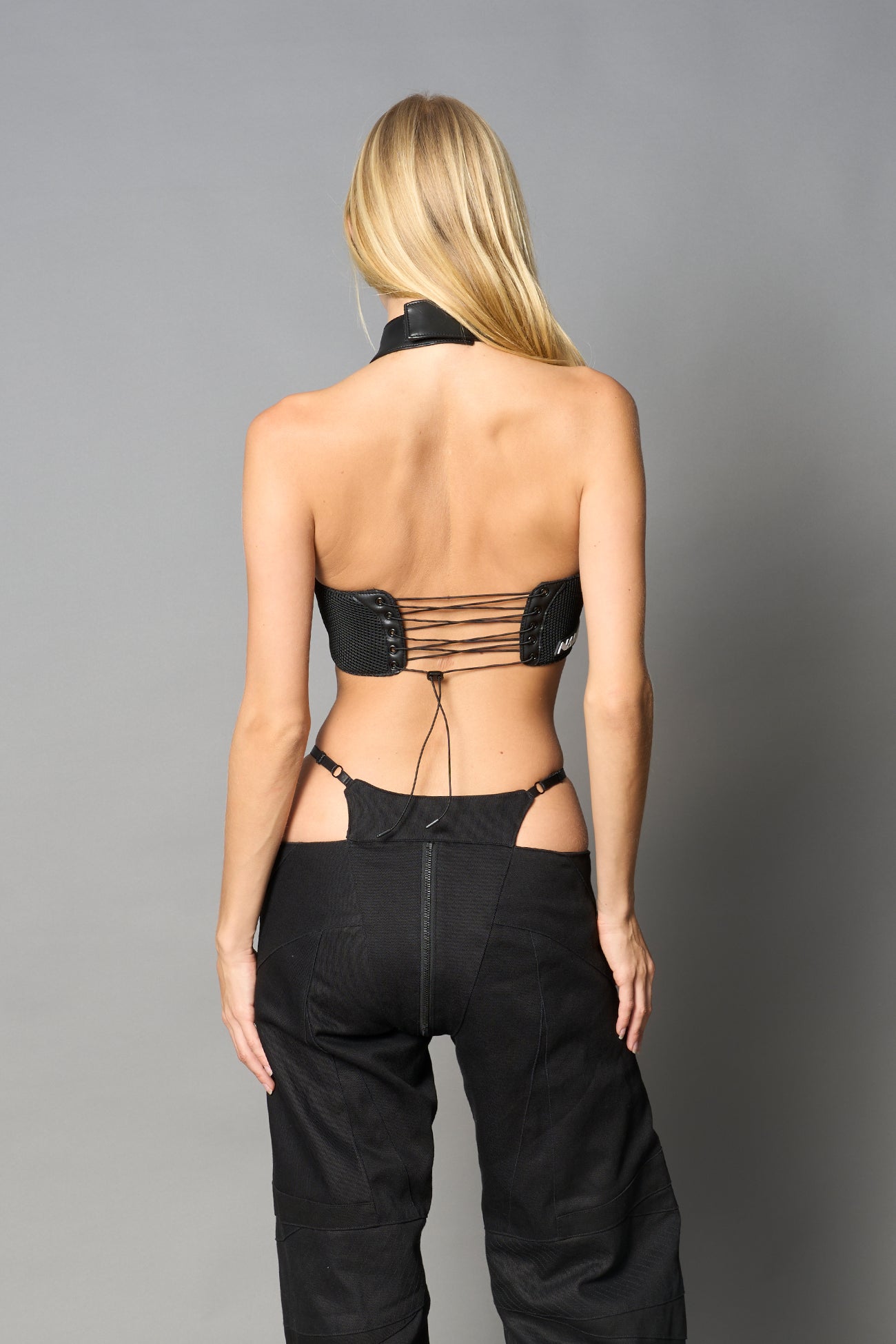Black vegan leather neckholder crop top with lace-up front, high neck collar, and mesh panel detailing – edgy moto-inspired top for clubwear or streetwear.
v