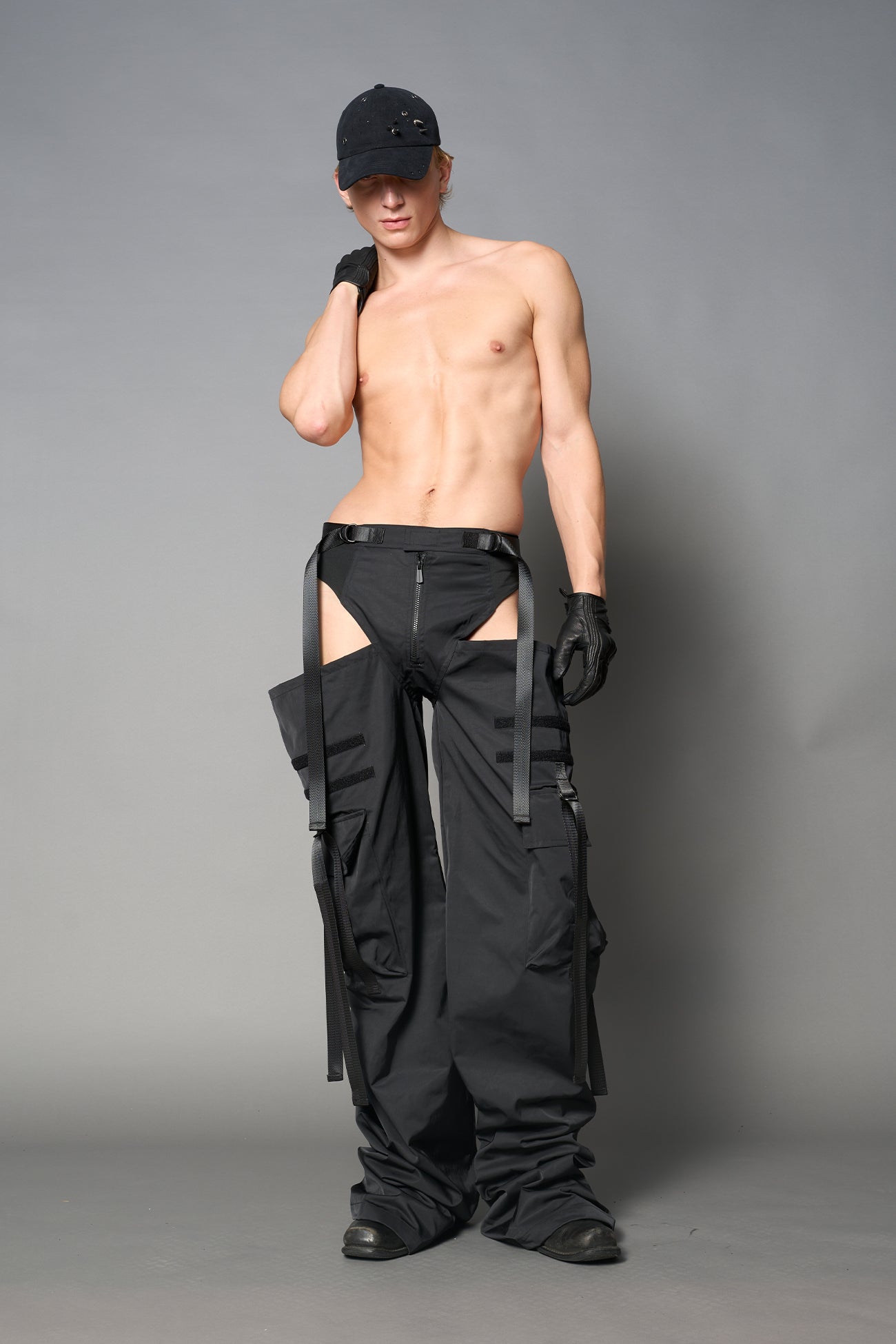 Black nylon cargo trousers with exposed high-cut panty waist, cut-out hips, oversized pockets, and adjustable utility straps – edgy streetwear and festival pants.