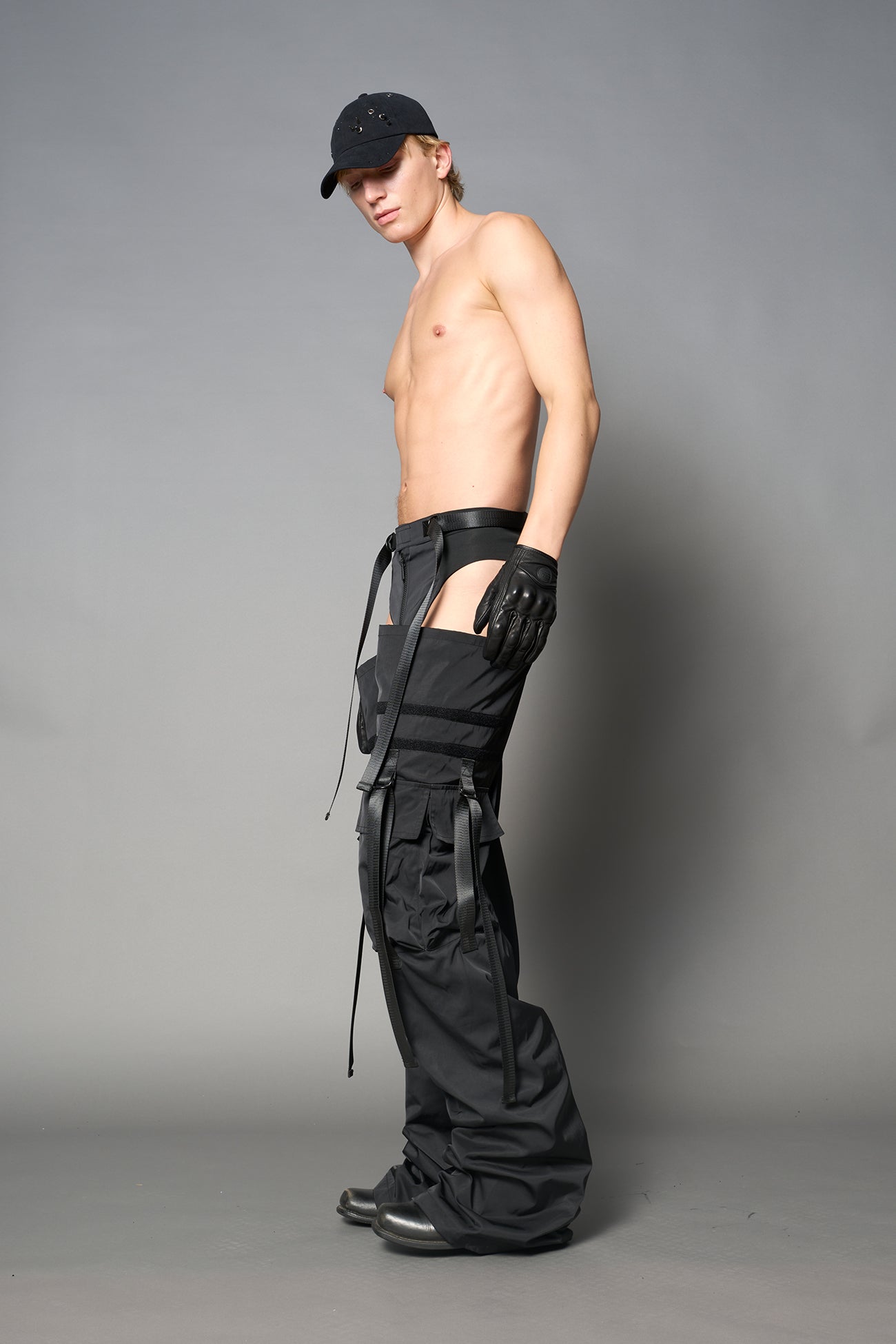 Black nylon cargo trousers with exposed high-cut panty waist, cut-out hips, oversized pockets, and adjustable utility straps – edgy streetwear and festival pants.