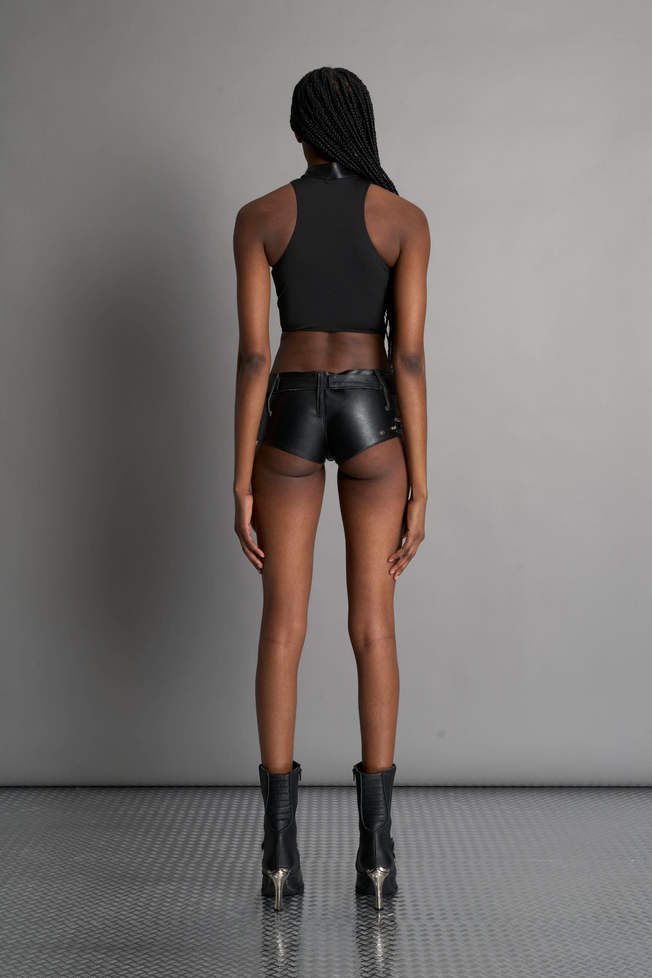 Namilia Piercing Top in black vegan leather featuring silver metal ring details, cutout design, and edgy Y2K-inspired crop top style. front view