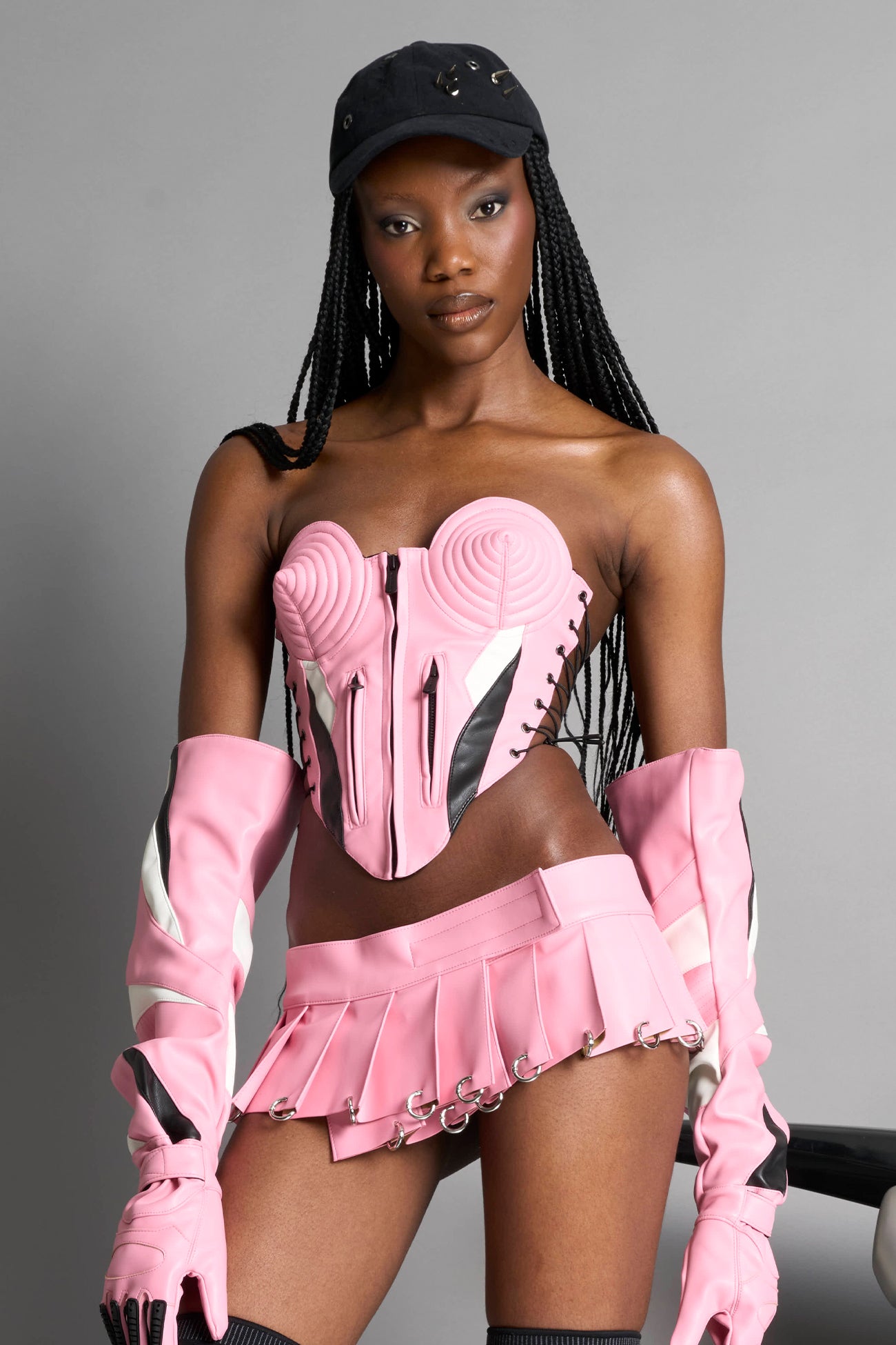 model wears pink vegan leather elbow-length moto gloves with motocross-style lines, contrast panelling, rubber finger protection, lycra webbing, and velcro wrist fasteners.