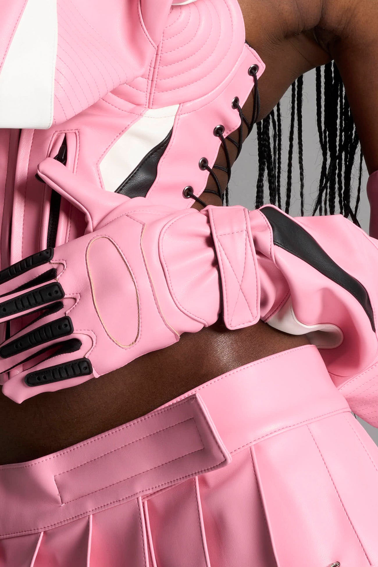 model wears pink vegan leather elbow-length moto gloves with motocross-style lines, contrast panelling, rubber finger protection, lycra webbing, and velcro wrist fasteners.
