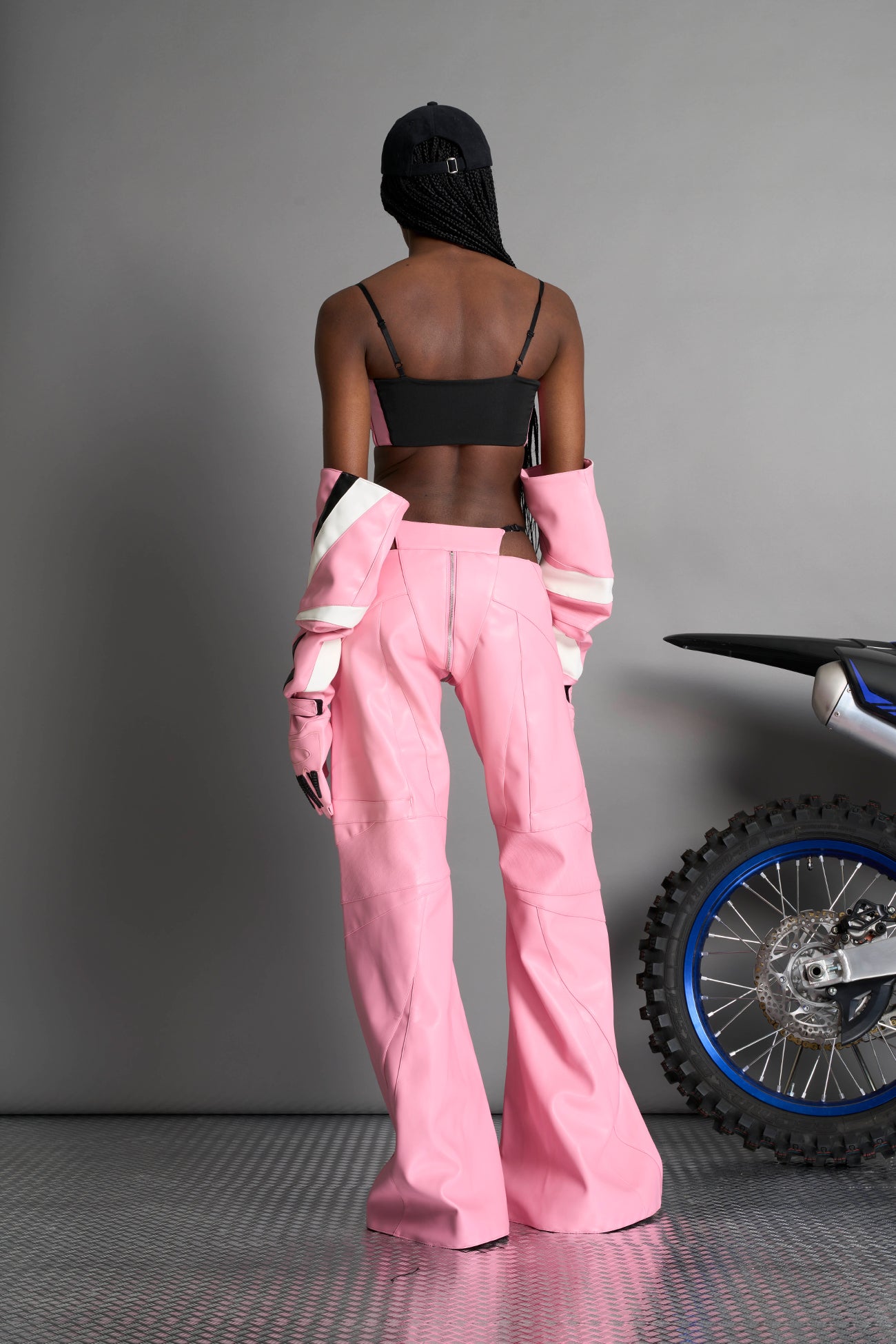 Low-rise flared pants in pink faux leather with bold side cut-outs and thong strap detailing. Featuring moto-style paneling, front zip closure, and a sculpted fit. A statement piece for rave, nightlife, and runway-inspired looks.