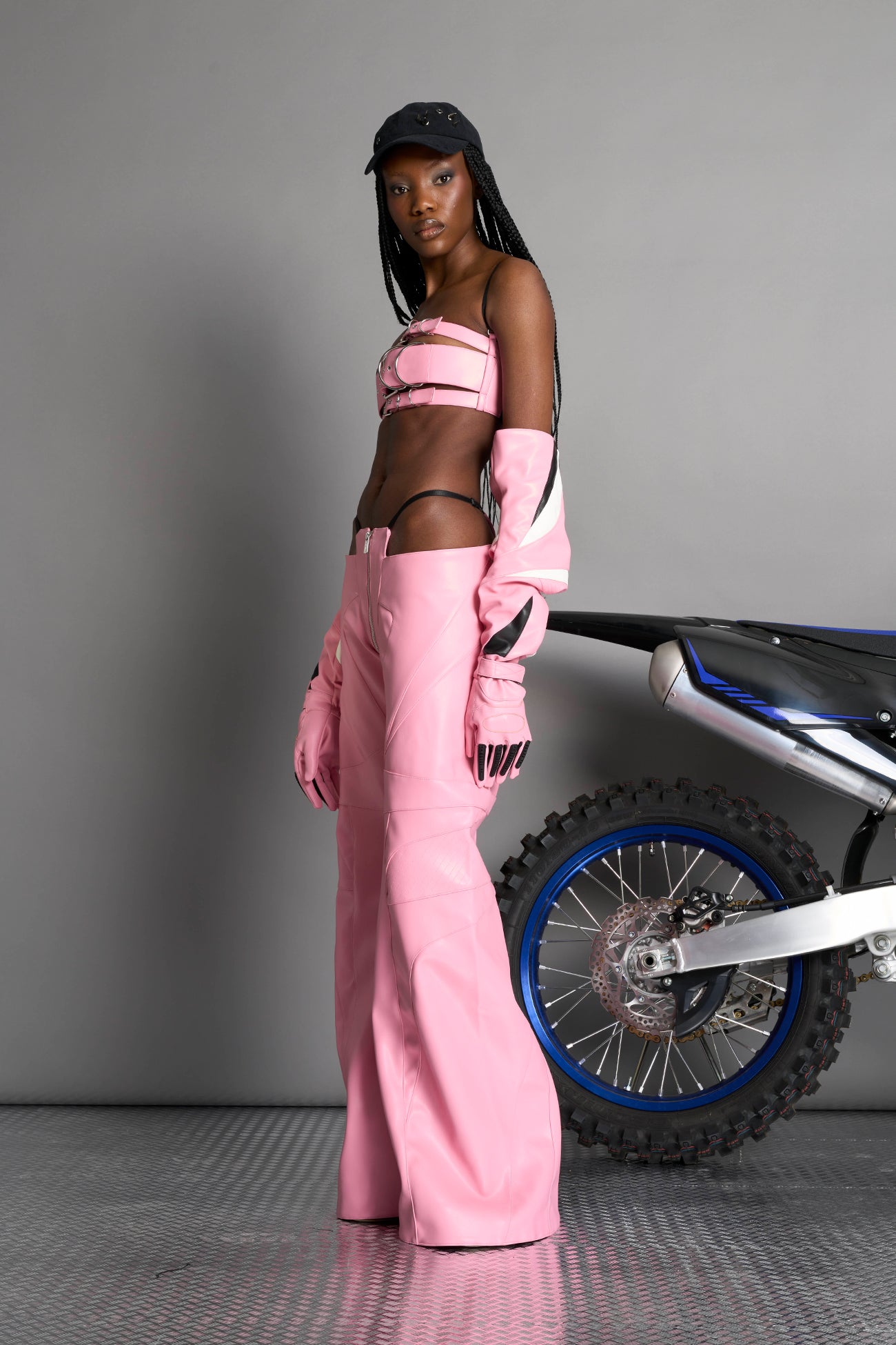 Low-rise flared pants in pink faux leather with bold side cut-outs and thong strap detailing. Featuring moto-style paneling, front zip closure, and a sculpted fit. A statement piece for rave, nightlife, and runway-inspired looks.