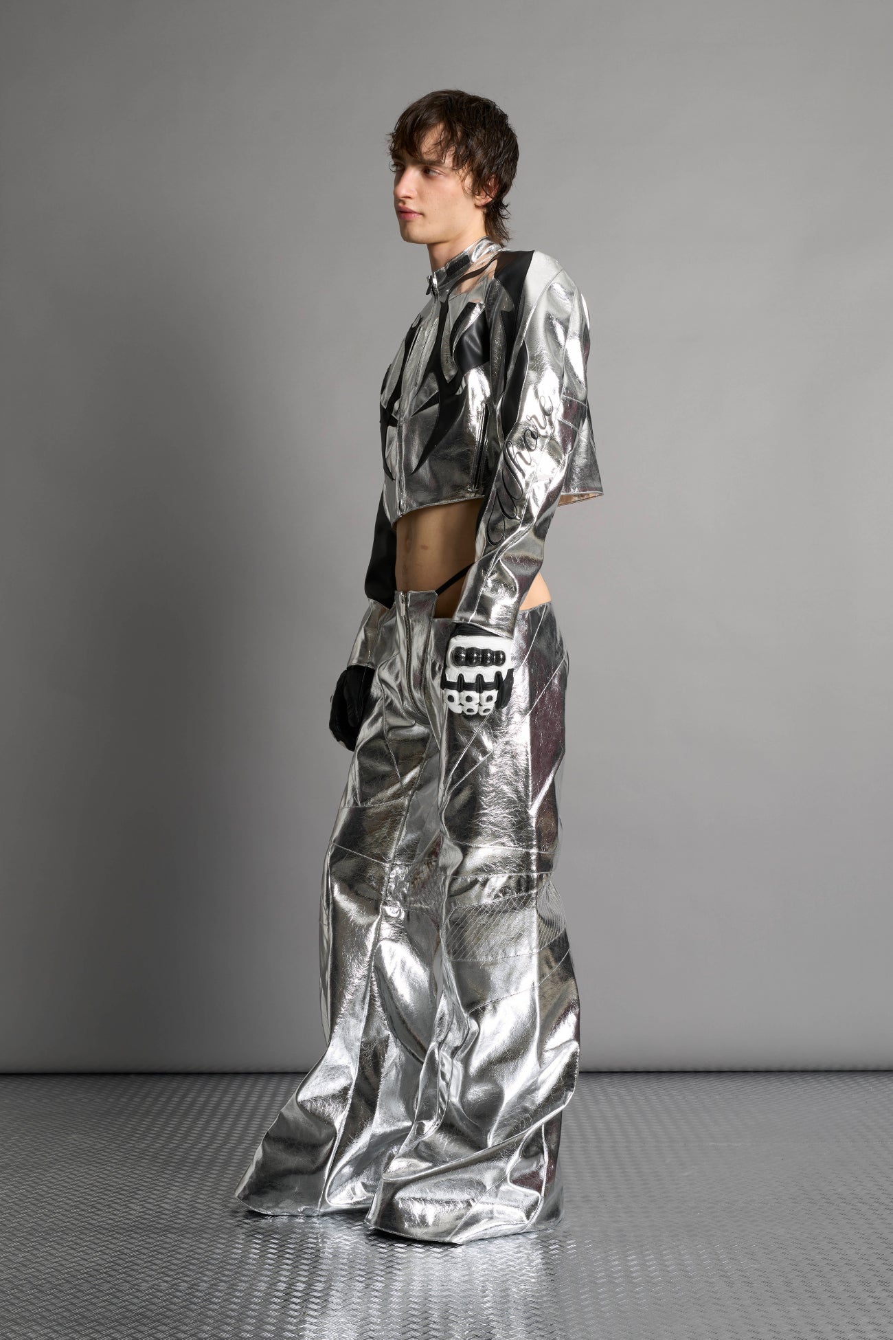 Low-rise flared pants in silver faux leather with bold side cut-outs and thong strap detailing. Featuring moto-style paneling, front zip closure, and a sculpted fit. A statement piece for rave, nightlife, and runway-inspired looks.