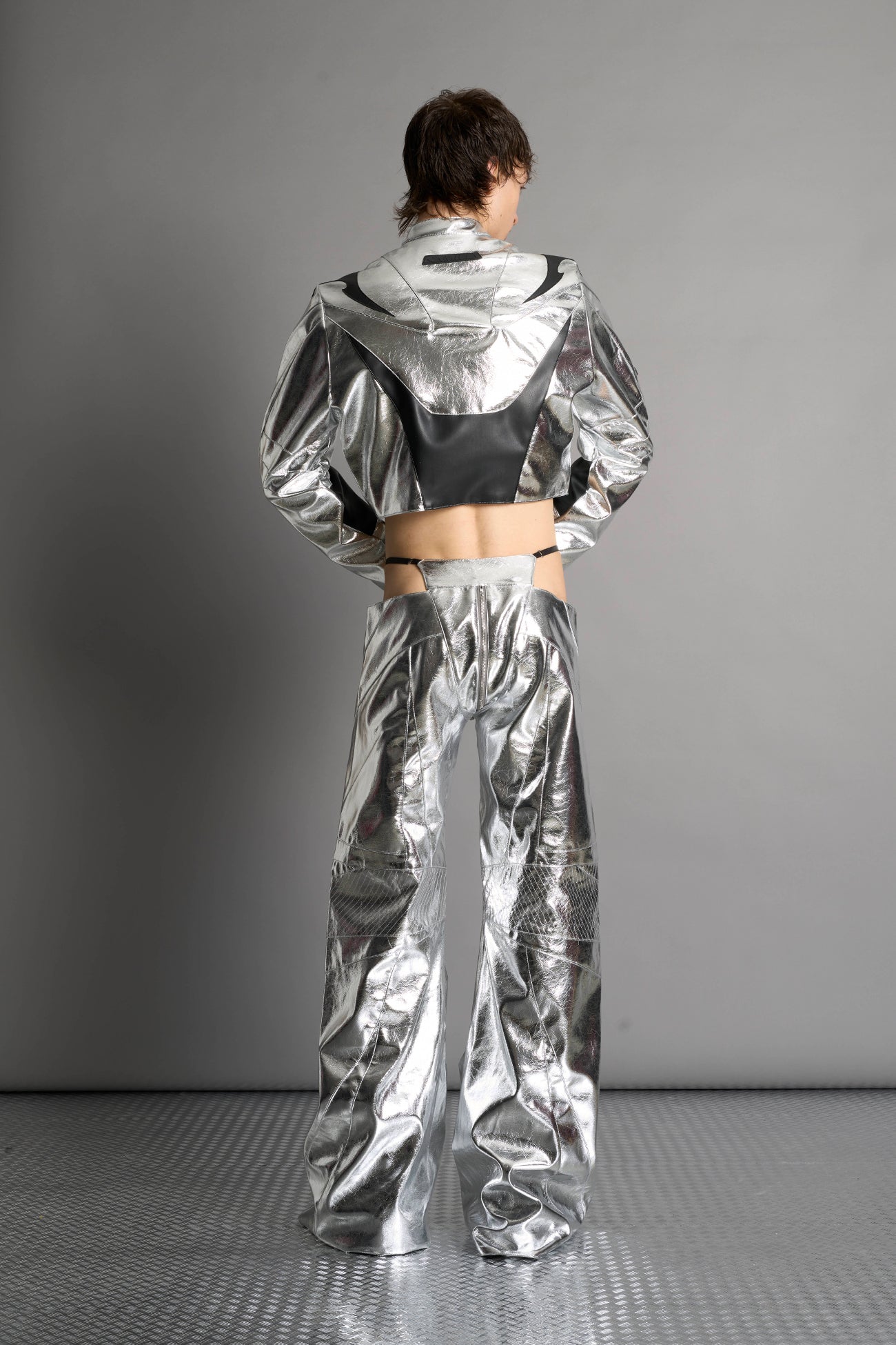 Low-rise flared pants in silver faux leather with bold side cut-outs and thong strap detailing. Featuring moto-style paneling, front zip closure, and a sculpted fit. A statement piece for rave, nightlife, and runway-inspired looks.