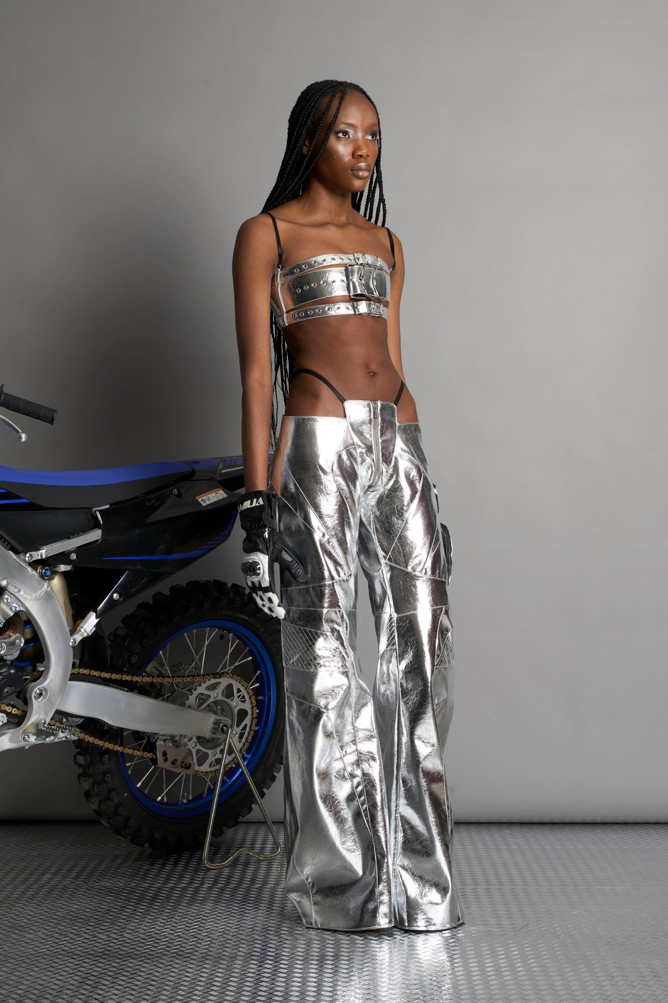 Low-rise flared pants in silver faux leather with bold side cut-outs and thong strap detailing. Featuring moto-style paneling, front zip closure, and a sculpted fit. A statement piece for rave, nightlife, and runway-inspired looks.