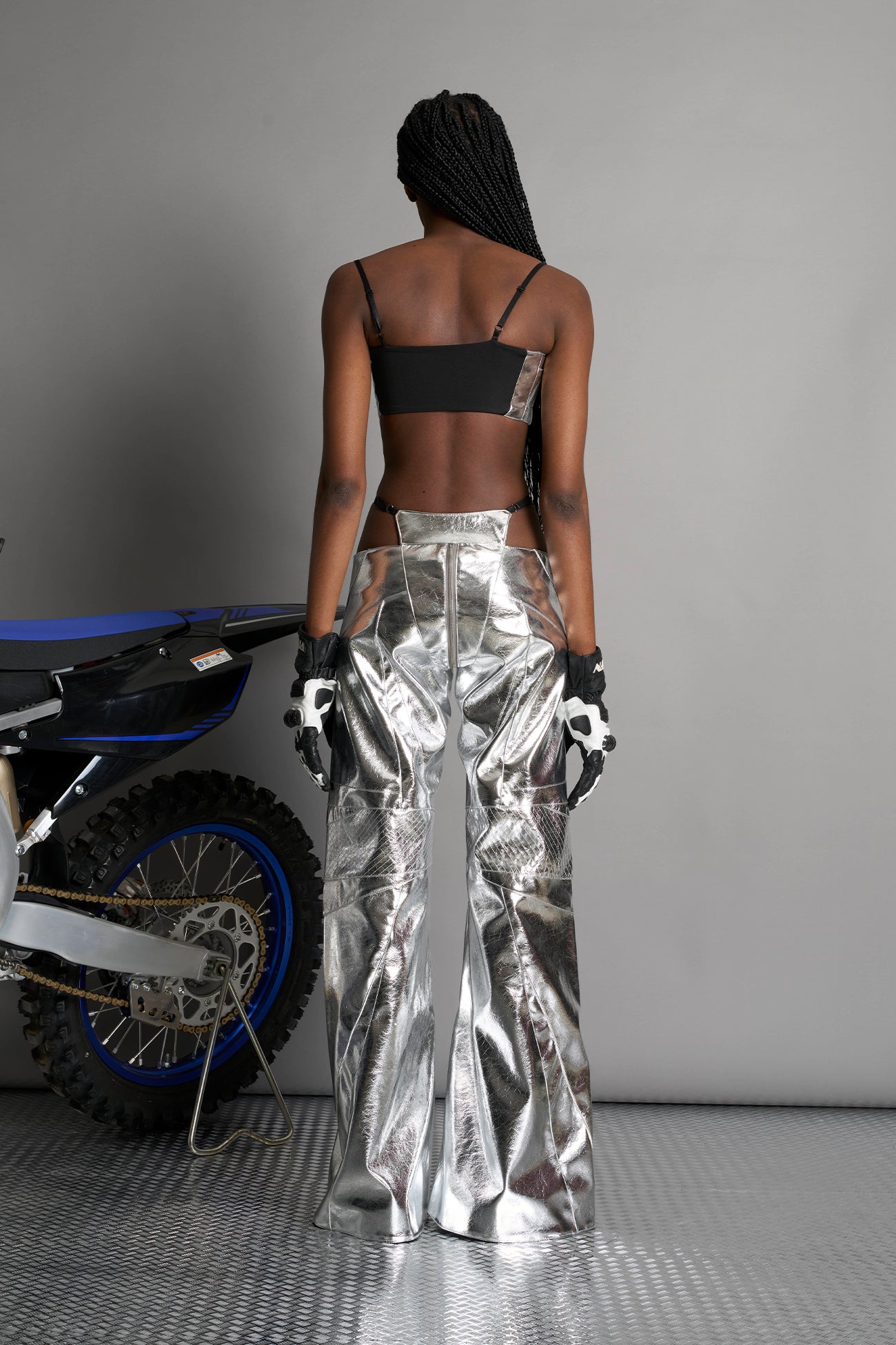 Low-rise flared pants in silver faux leather with bold side cut-outs and thong strap detailing. Featuring moto-style paneling, front zip closure, and a sculpted fit. A statement piece for rave, nightlife, and runway-inspired looks.