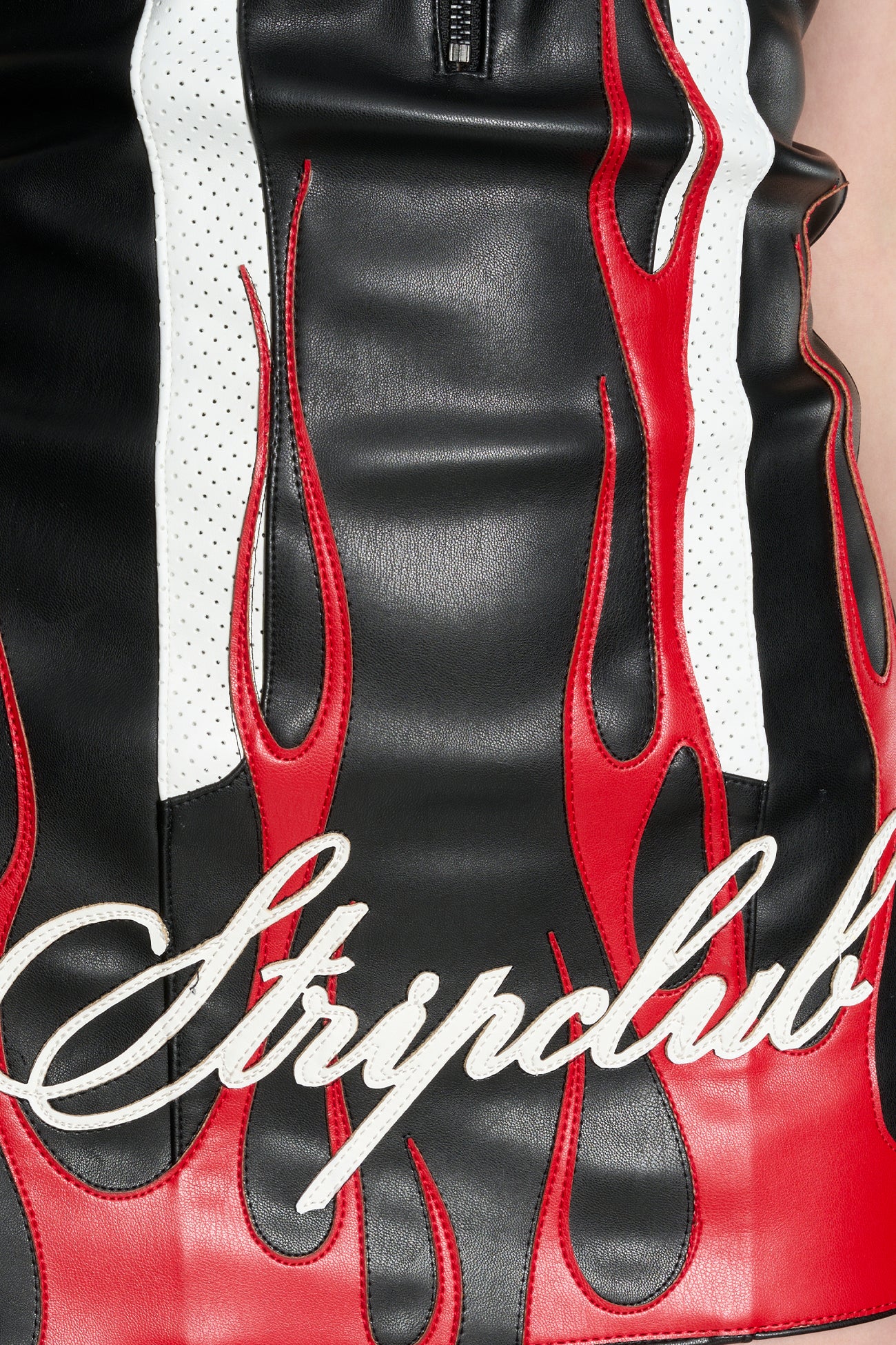 Model wears a short black/red vegan leather halter dress with open back, motocross paneling, red flame topstitching, ‘stripclub’ embroidery, and adjustable back straps.