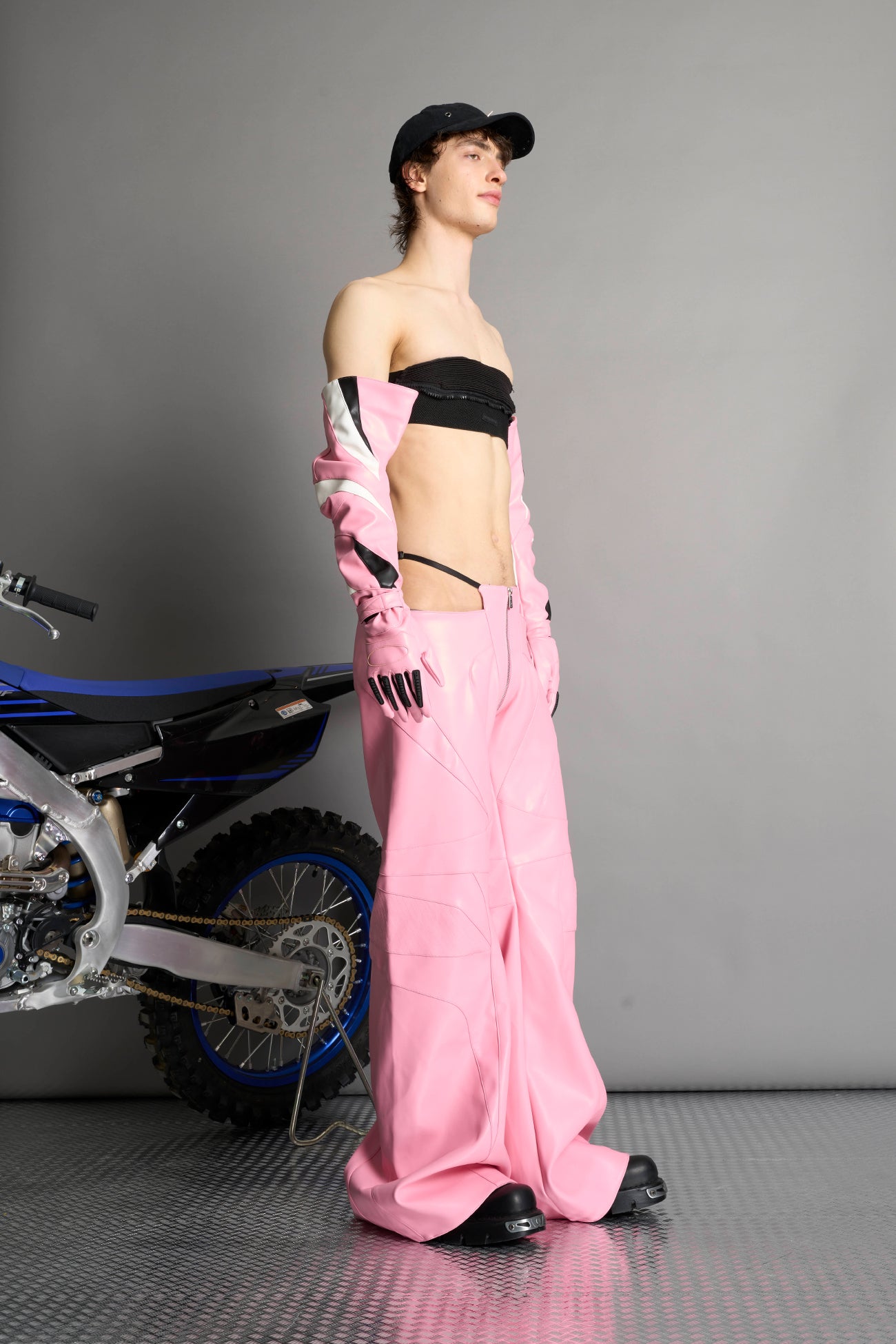 Low-rise flared pants in pink faux leather with bold side cut-outs and thong strap detailing. Featuring moto-style paneling, front zip closure, and a sculpted fit. A statement piece for rave, nightlife, and runway-inspired looks.