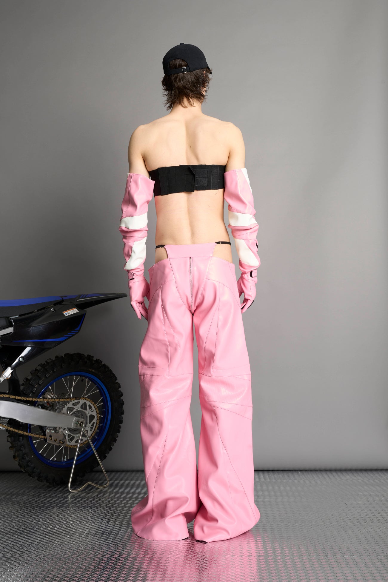 Low-rise flared pants in pink faux leather with bold side cut-outs and thong strap detailing. Featuring moto-style paneling, front zip closure, and a sculpted fit. A statement piece for rave, nightlife, and runway-inspired looks.