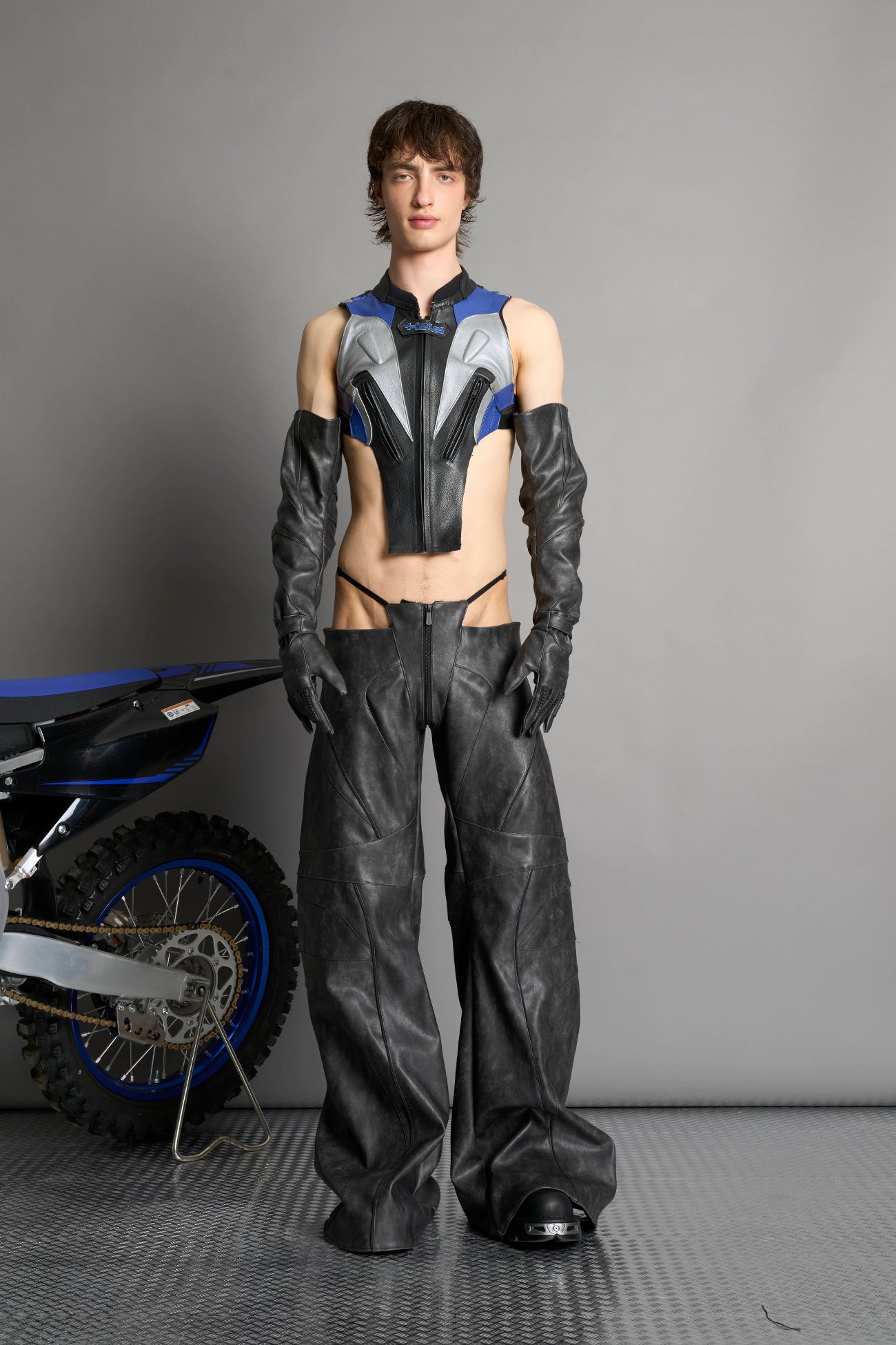 Low-rise flared pants in washed black faux leather with bold side cut-outs and thong strap detailing. Featuring moto-style paneling, front zip closure, and a sculpted fit. A statement piece for rave, nightlife, and runway-inspired looks.