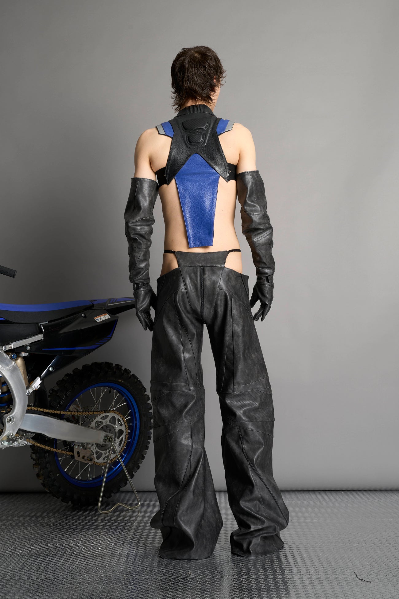 Low-rise flared pants in washed black faux leather with bold side cut-outs and thong strap detailing. Featuring moto-style paneling, front zip closure, and a sculpted fit. A statement piece for rave, nightlife, and runway-inspired looks.