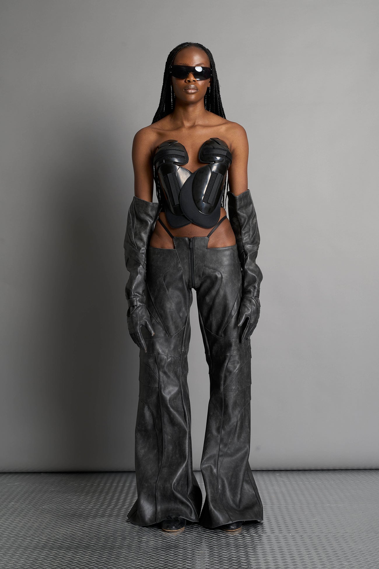 Low-rise flared pants in washed black faux leather with bold side cut-outs and thong strap detailing. Featuring moto-style paneling, front zip closure, and a sculpted fit. A statement piece for rave, nightlife, and runway-inspired looks.