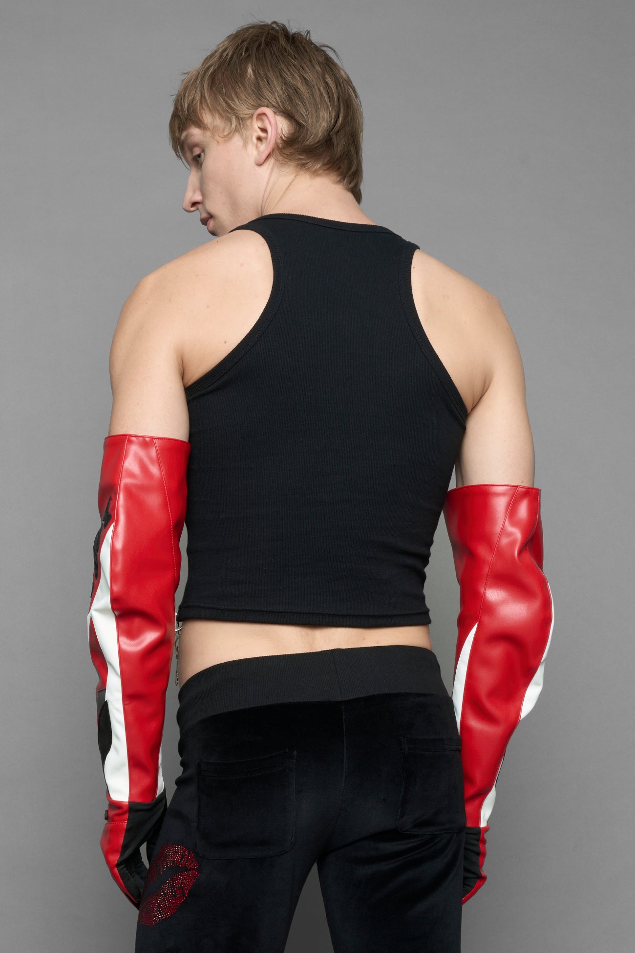 A model wearing a black halter crop top with red and silver 'I <heart> PLAYBOY Namilia' graphic, paired with black pants featuring a red lip print