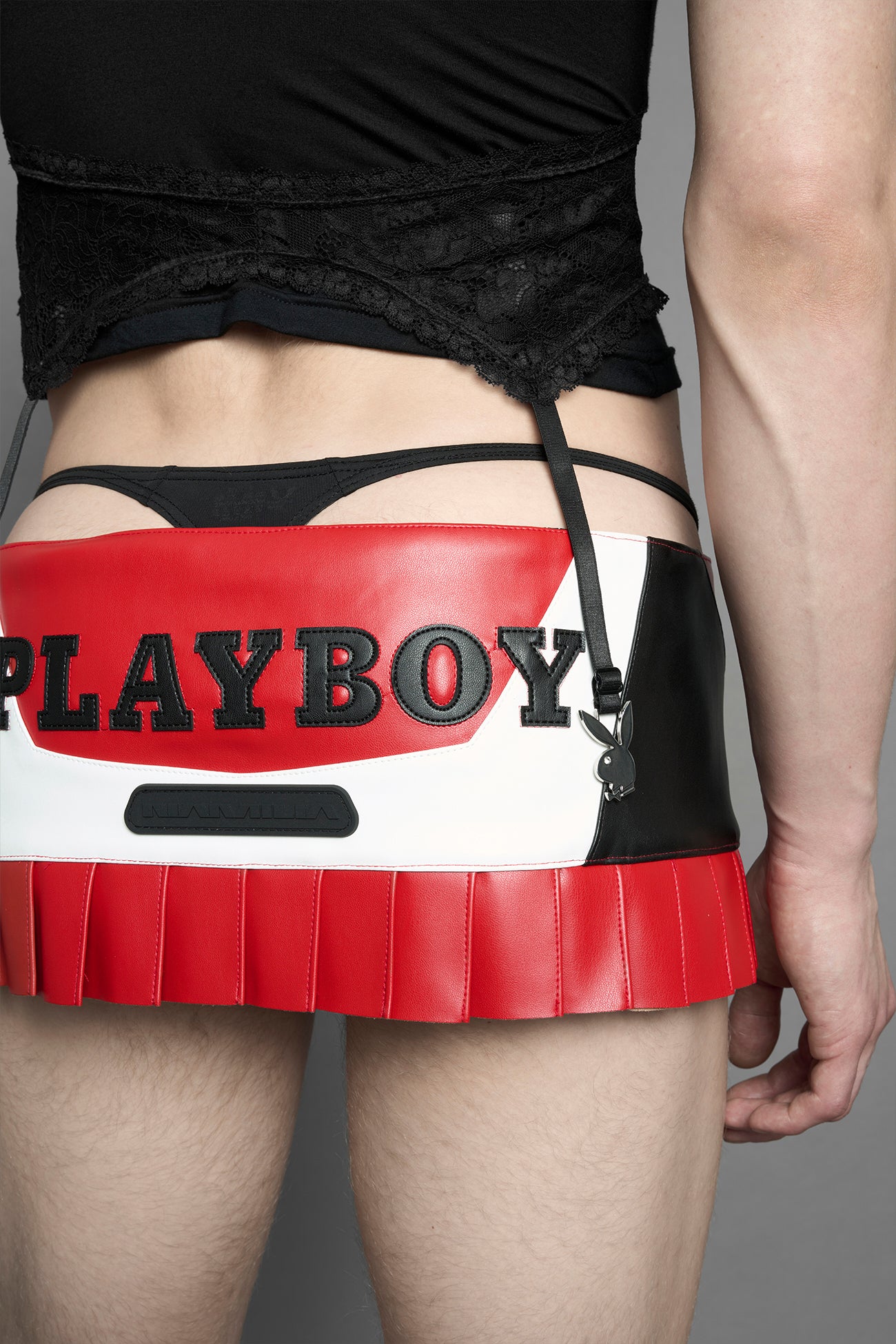 model wearing a red vegan leather wrap mini skirt with a black PU leather Bunny embroidery and a branded 'Playboy X Namilia' Rubbertag.