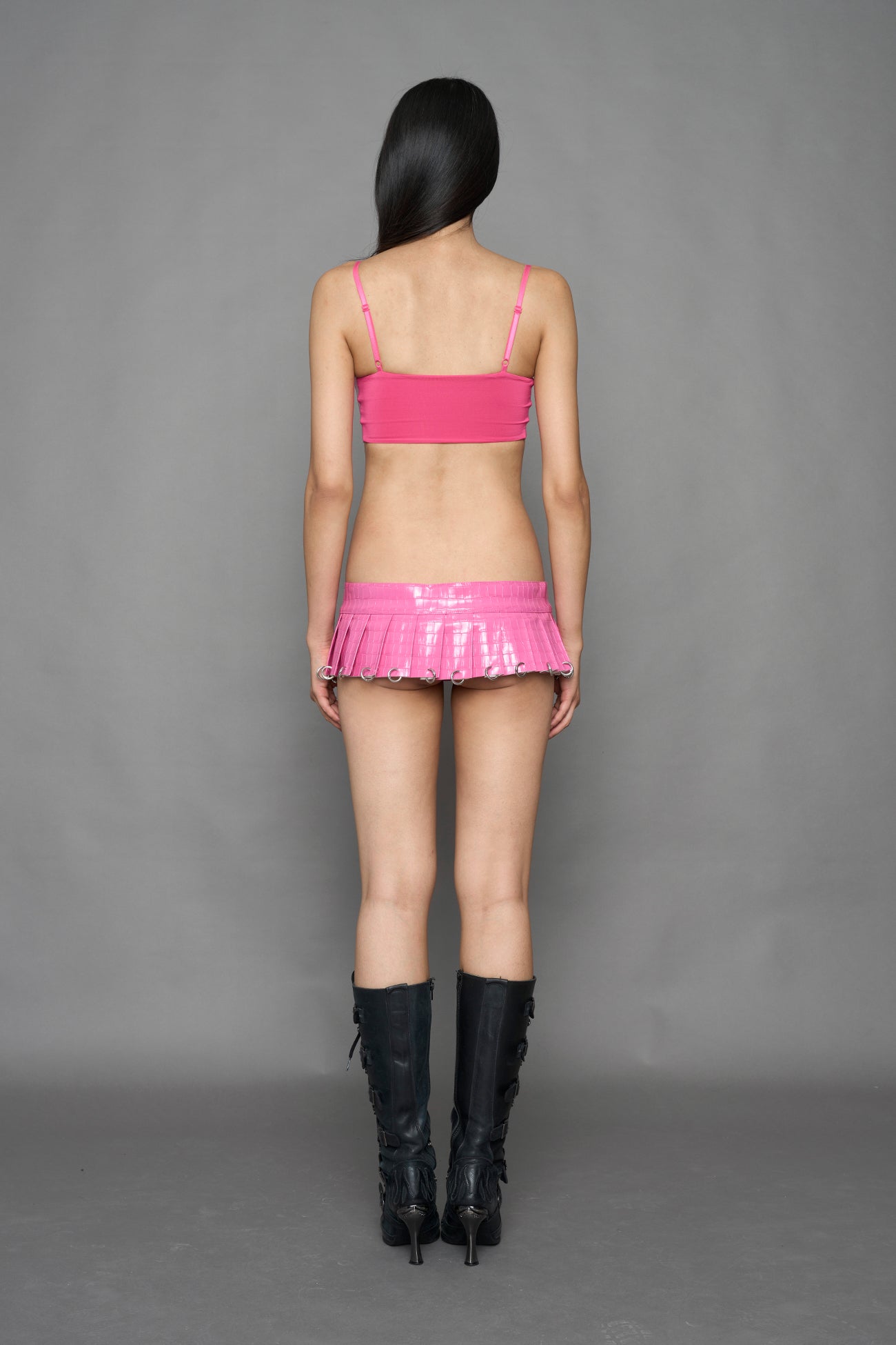 model wearing pink croc vegan leather pleated mini skirt with ring details