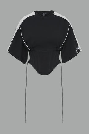 Front view of model in washed-black Namilia Corset-T shirt with sculpted corset-style waist, curved hemline, and oversized sleeves