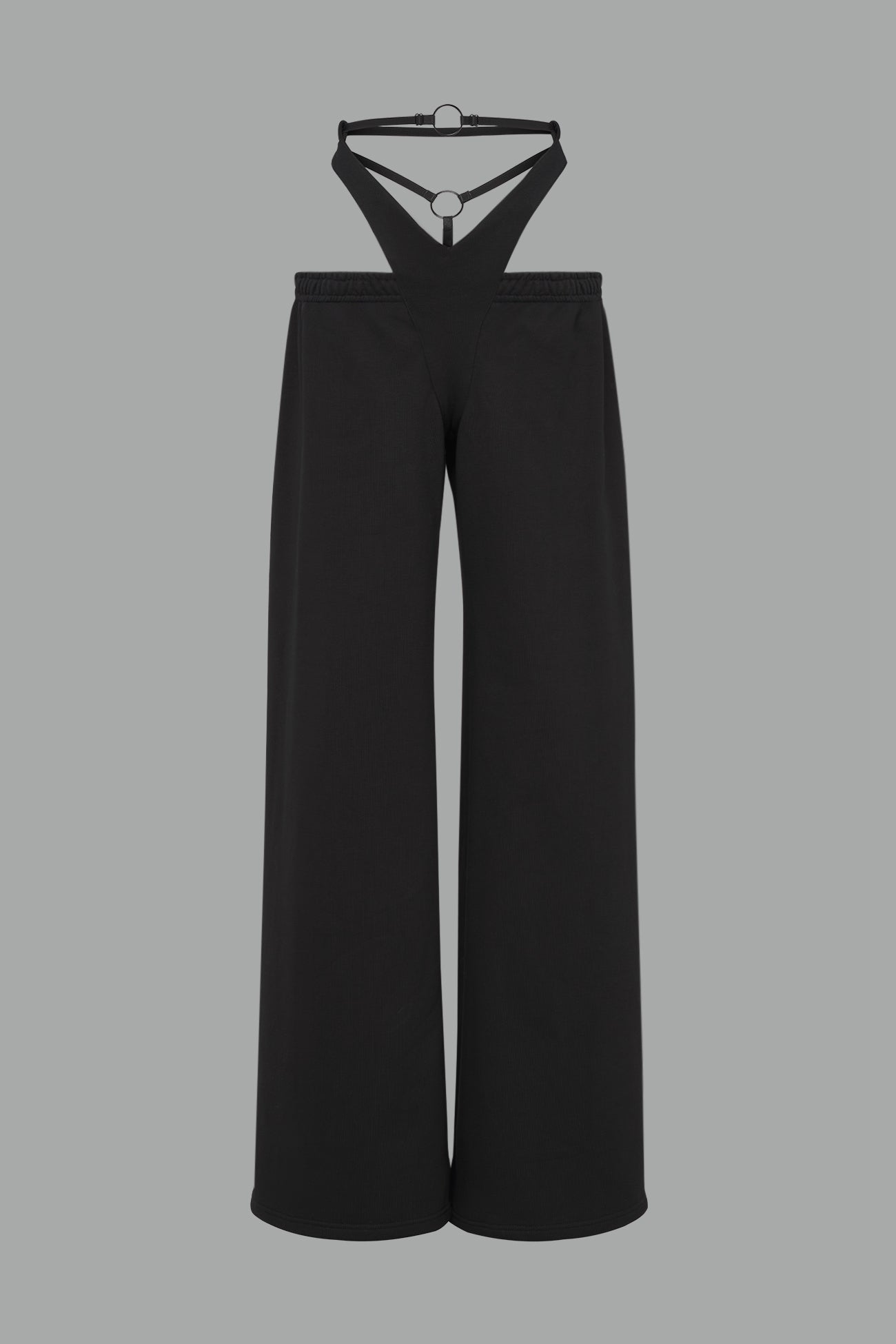 Model wearing low-rise black wide-leg pants featuring a V-shaped waistband and detachable thong strap detail.