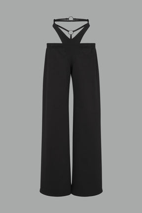 Model wearing low-rise black wide-leg pants featuring a V-shaped waistband and detachable thong strap detail.
