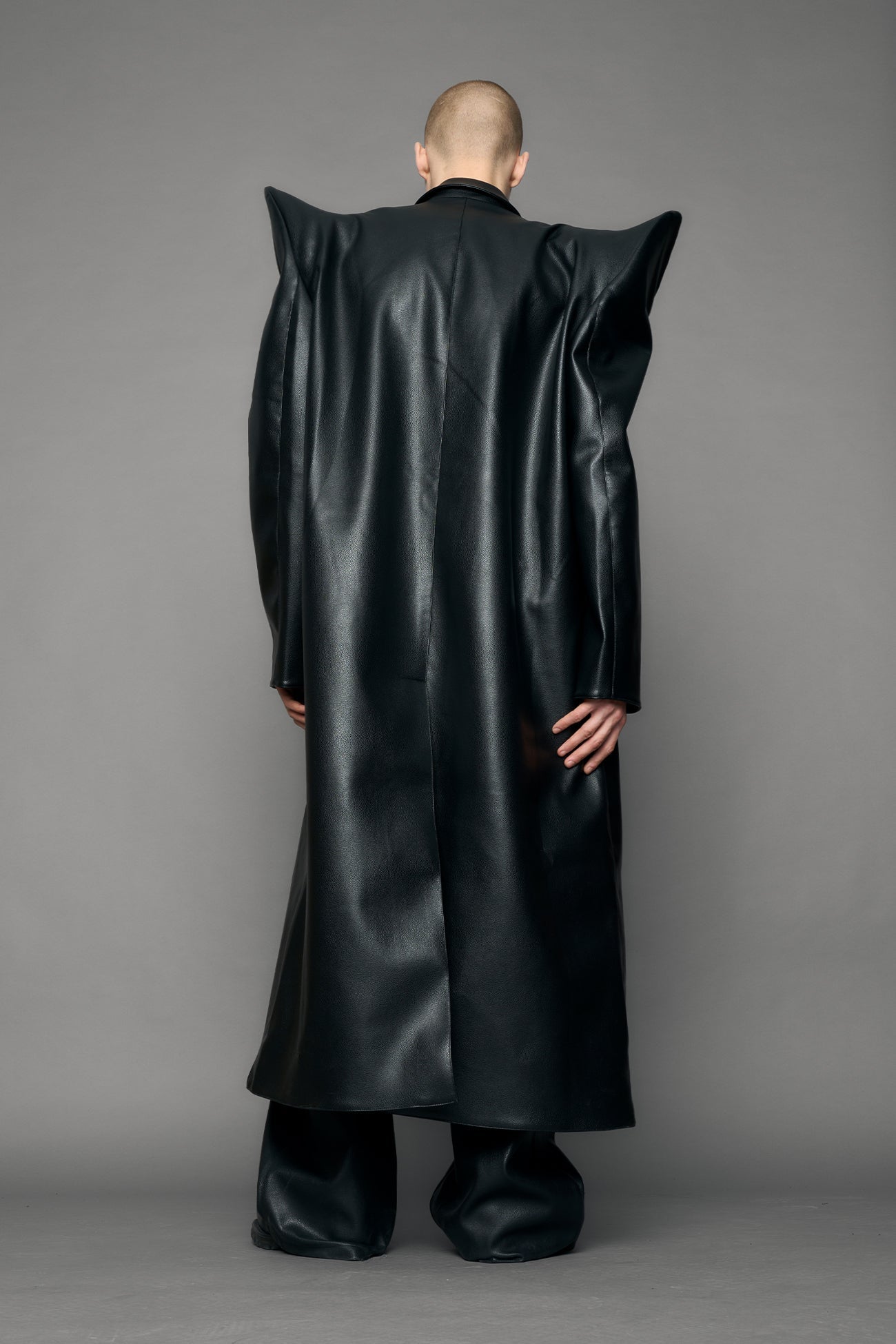 model wearing black pu leather coat with sharp shoulder design