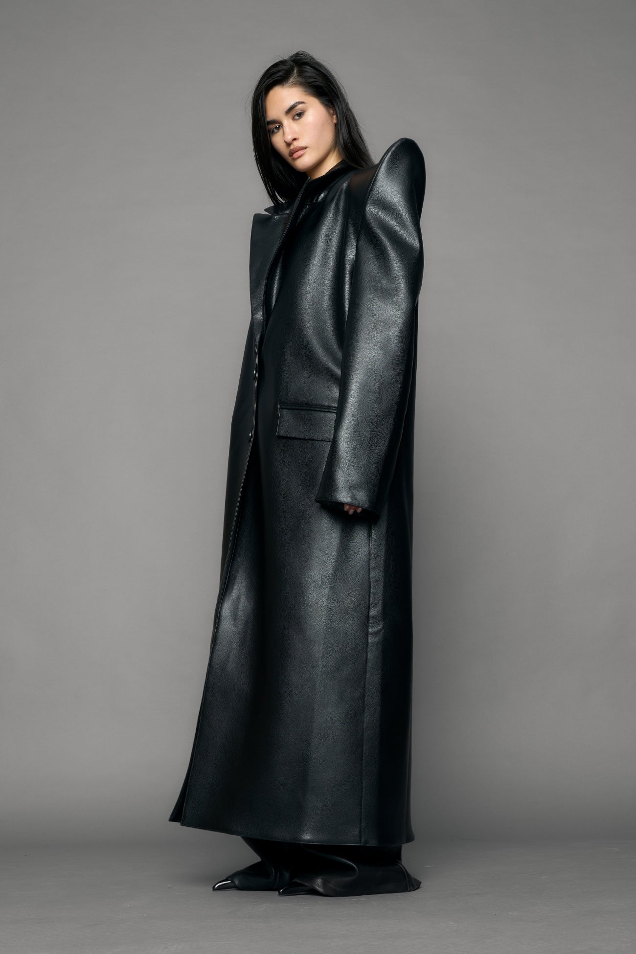 model wearing black pu leather coat with sharp shoulder design