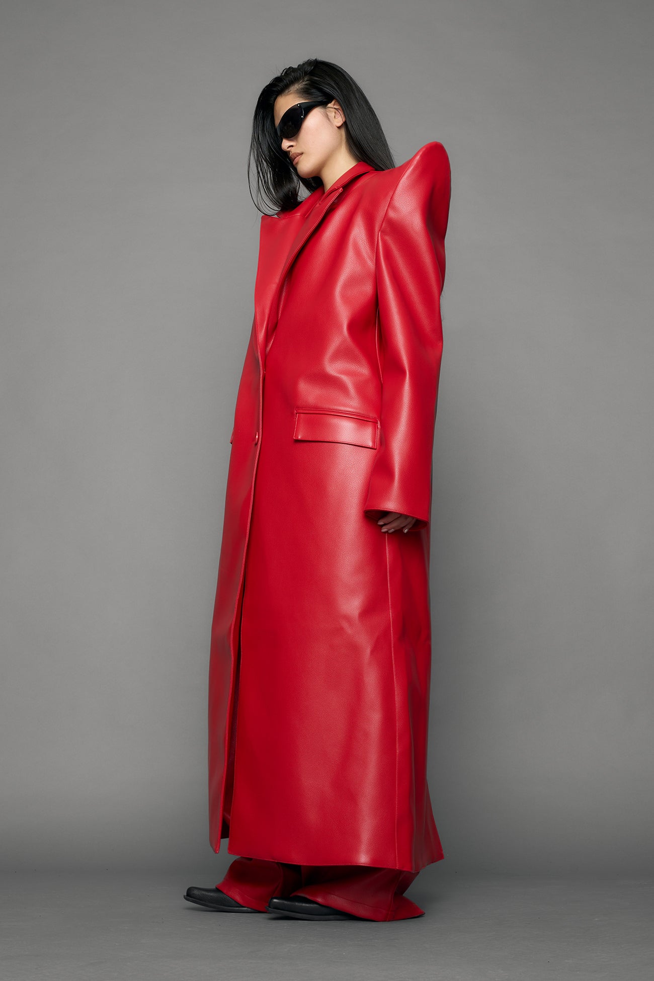 model wearing red pu leather coat with sharp shoulder design