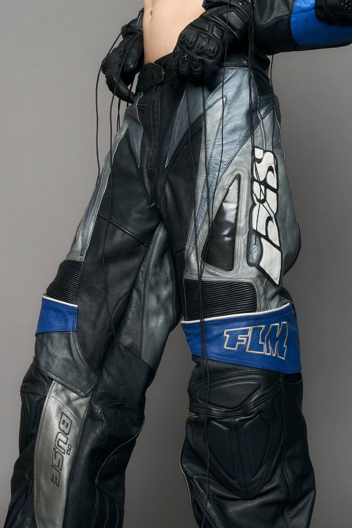 model wearing a motocross pants with silver and black accents on a gray background