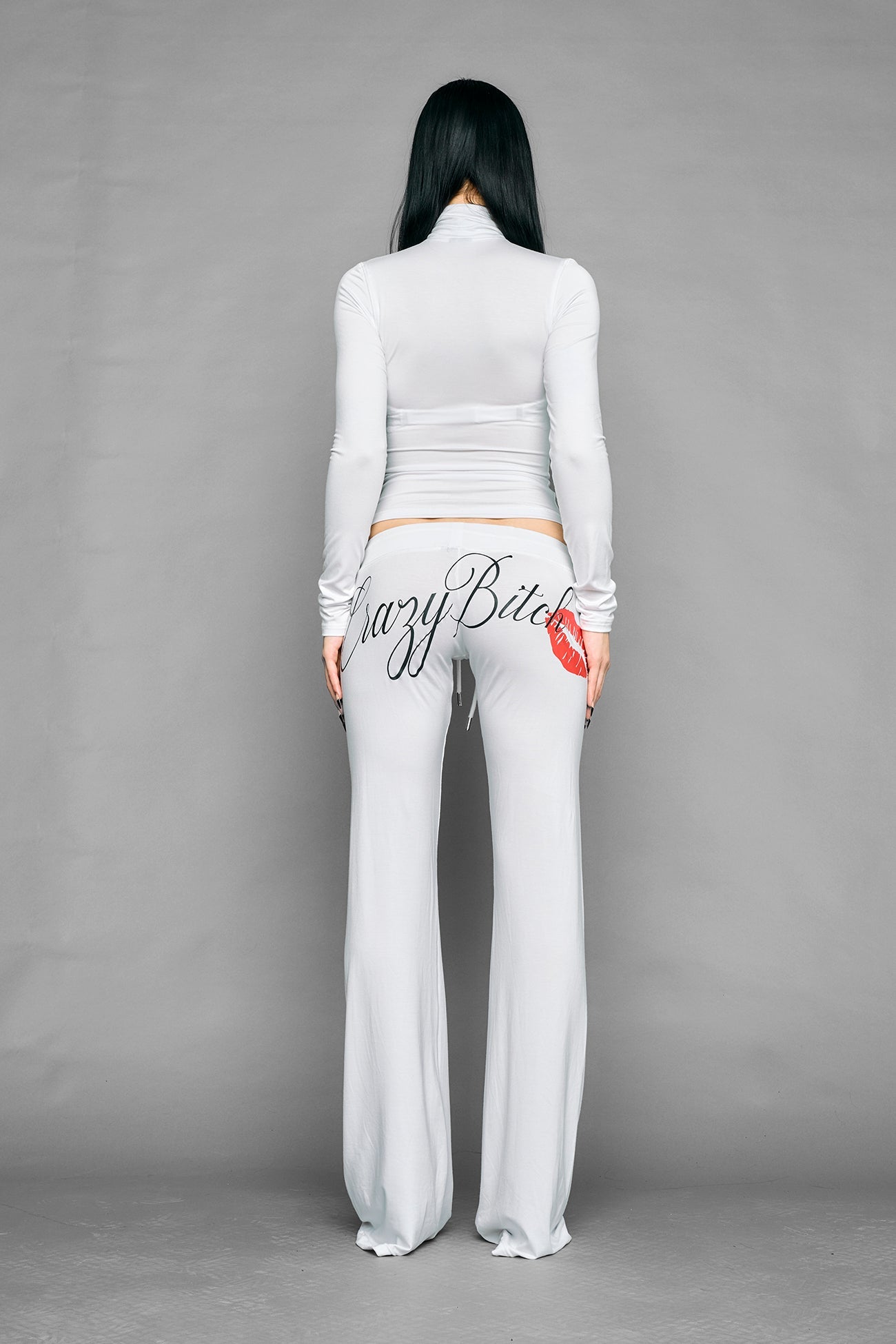white crazy jersey pants with high waist rib waistband drawstring and back graphic print on model studio ecom photo