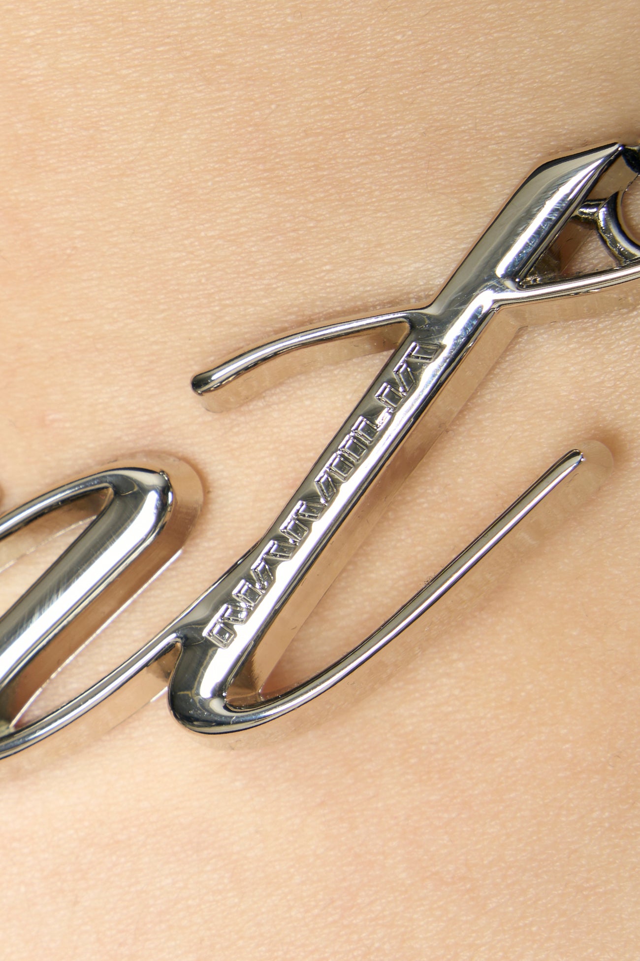 Model wearing black metal logo thong with adjustable straps, styled with cropped tee and heels, side view