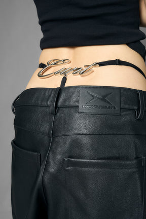 Model wearing black metal logo thong with adjustable straps, styled with cropped tee and heels, side view