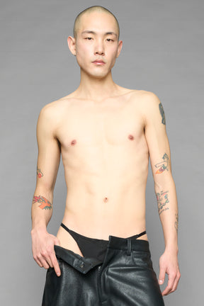 Model wearing black metal logo thong with adjustable straps