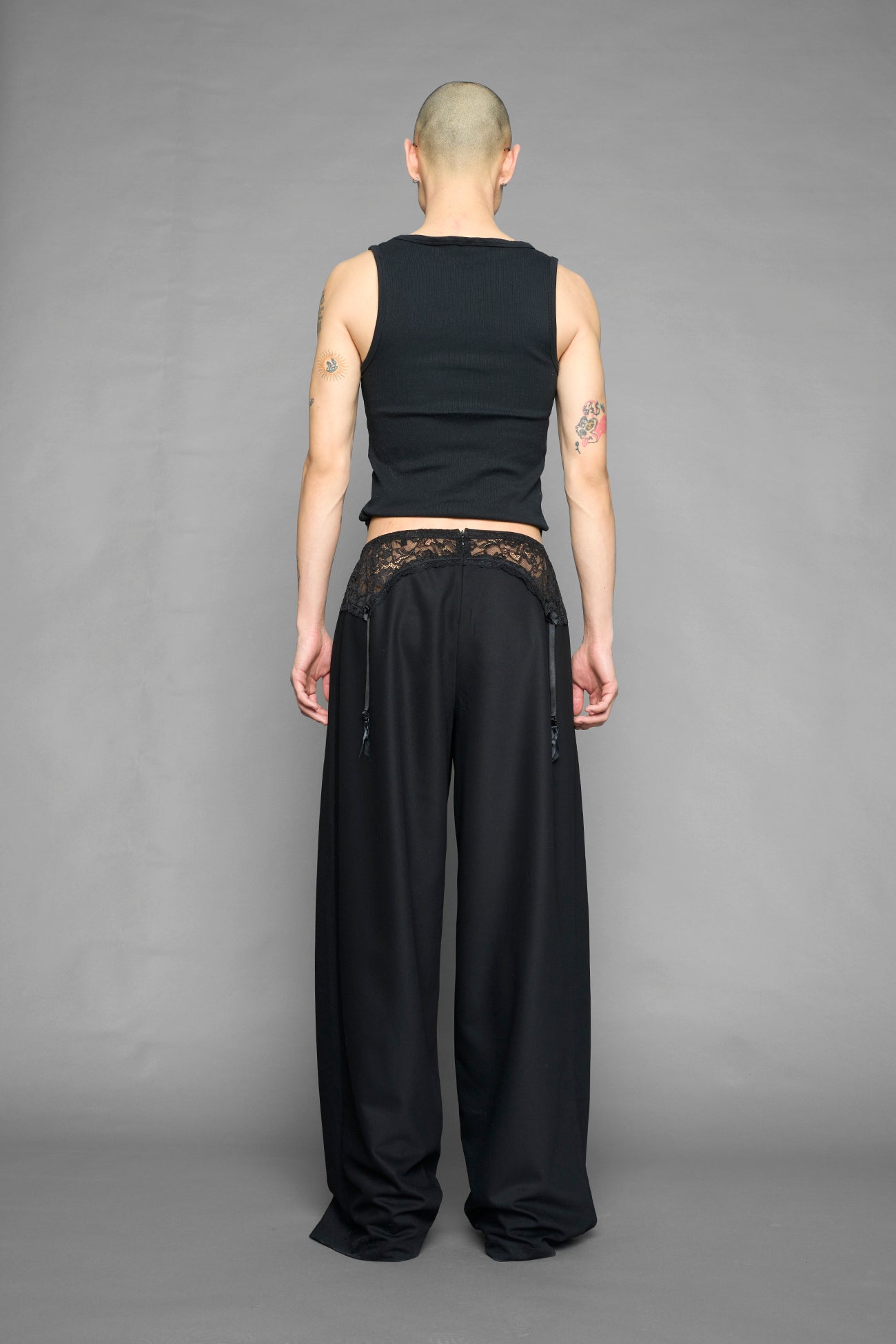 model wearing black baggy suiting pants with garter lace waist detail
