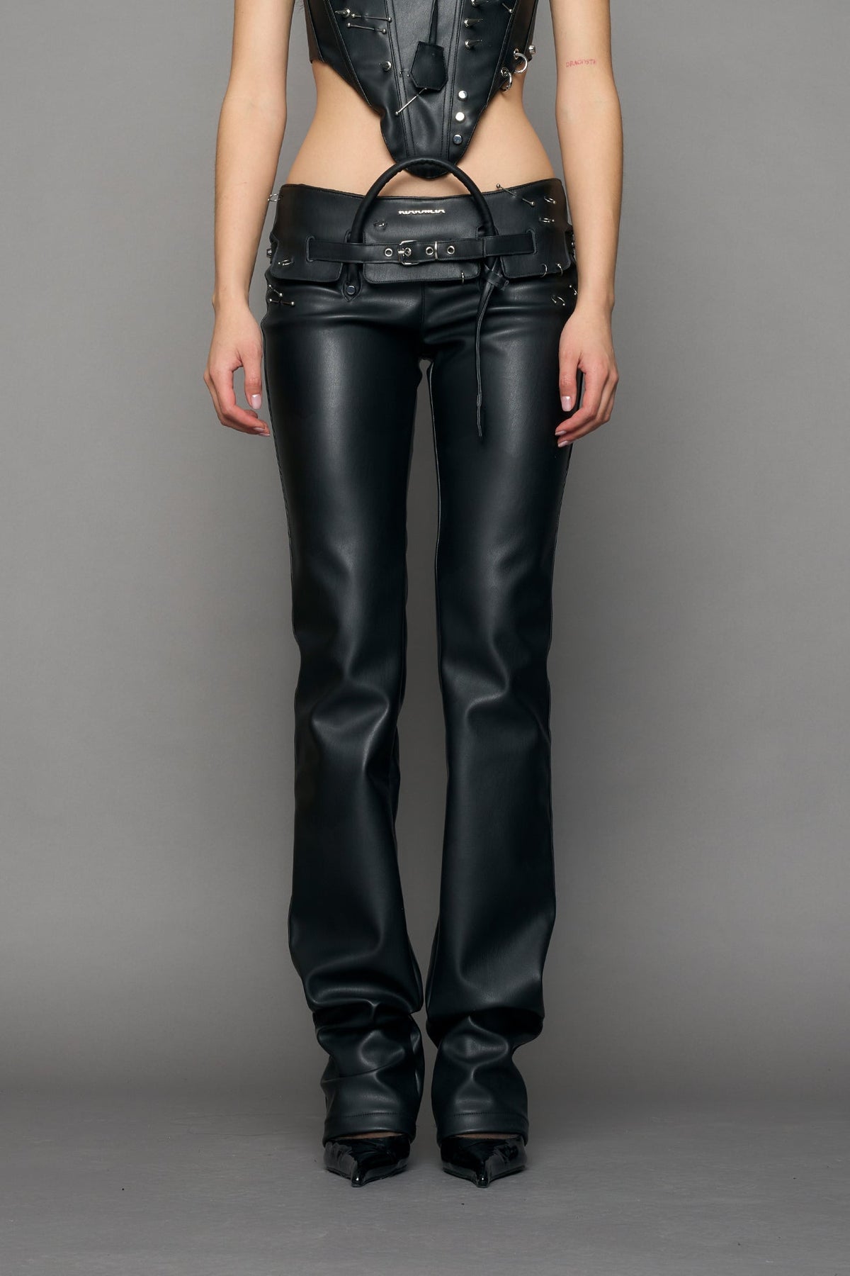 model wearing black pu leather studded handbag pants