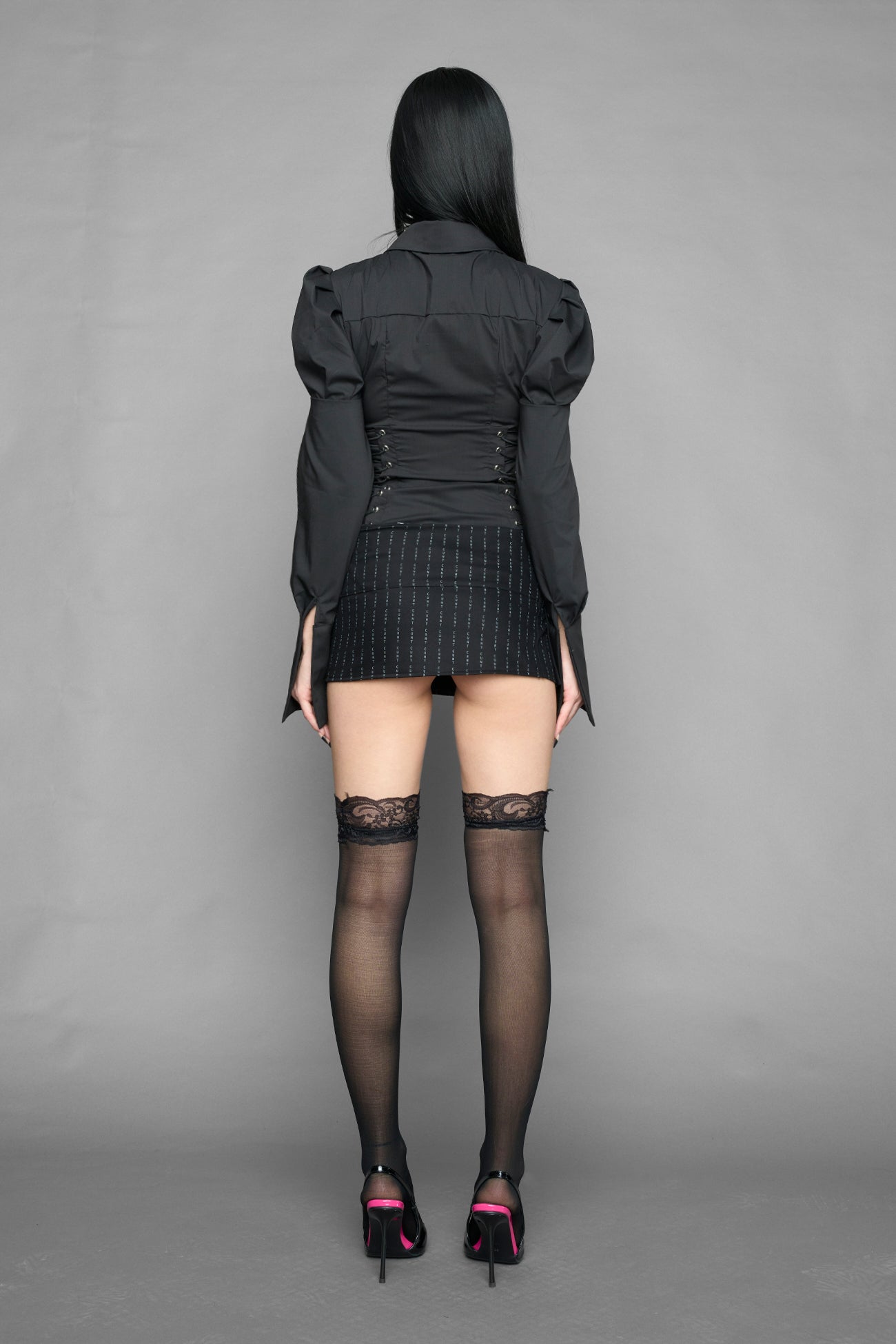black print pleated micro mini skirt with low rise waistband and buckle strap detail worn by model studio ecommerce image