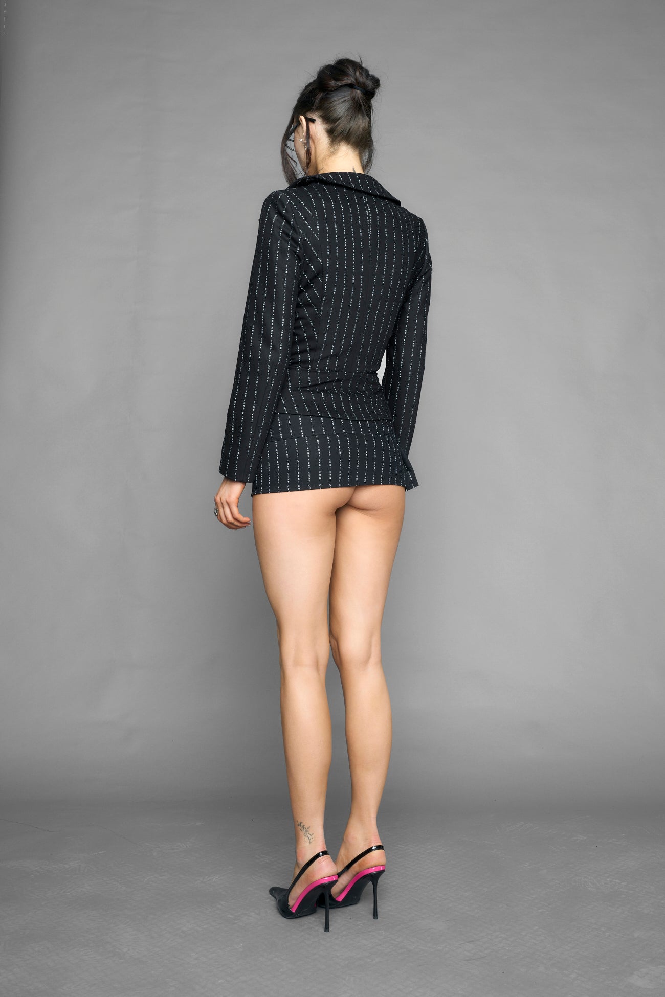 black print pleated micro mini skirt with low rise waistband and buckle strap detail worn by model studio ecommerce image