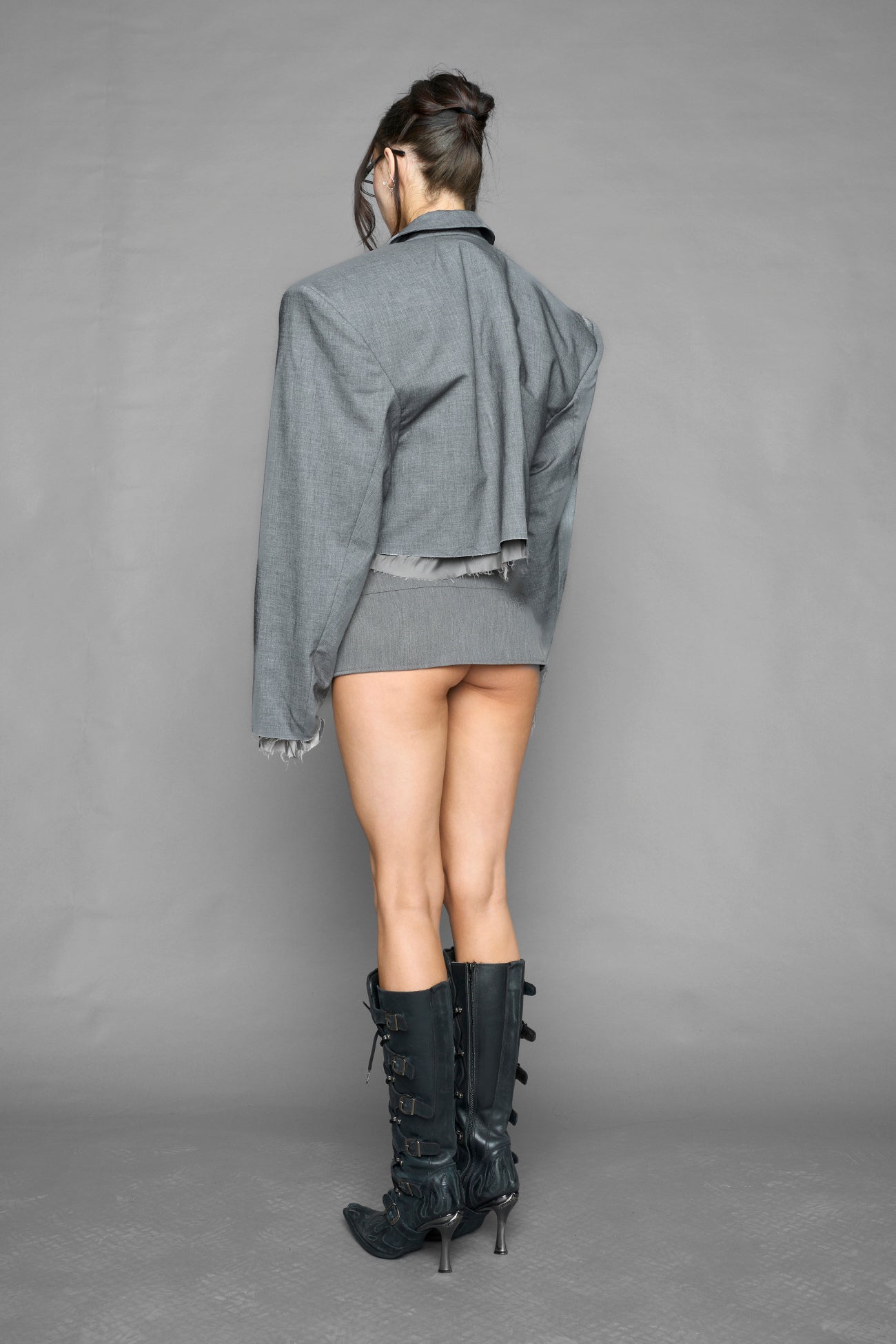 grey pleated micro mini skirt with low rise waistband and buckle strap detail worn by model studio ecommerce image