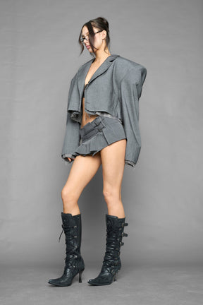 grey pleated micro mini skirt with low rise waistband and buckle strap detail worn by model studio ecommerce image
