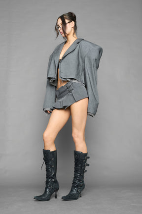 grey pleated micro mini skirt with low rise waistband and buckle strap detail worn by model studio ecommerce image