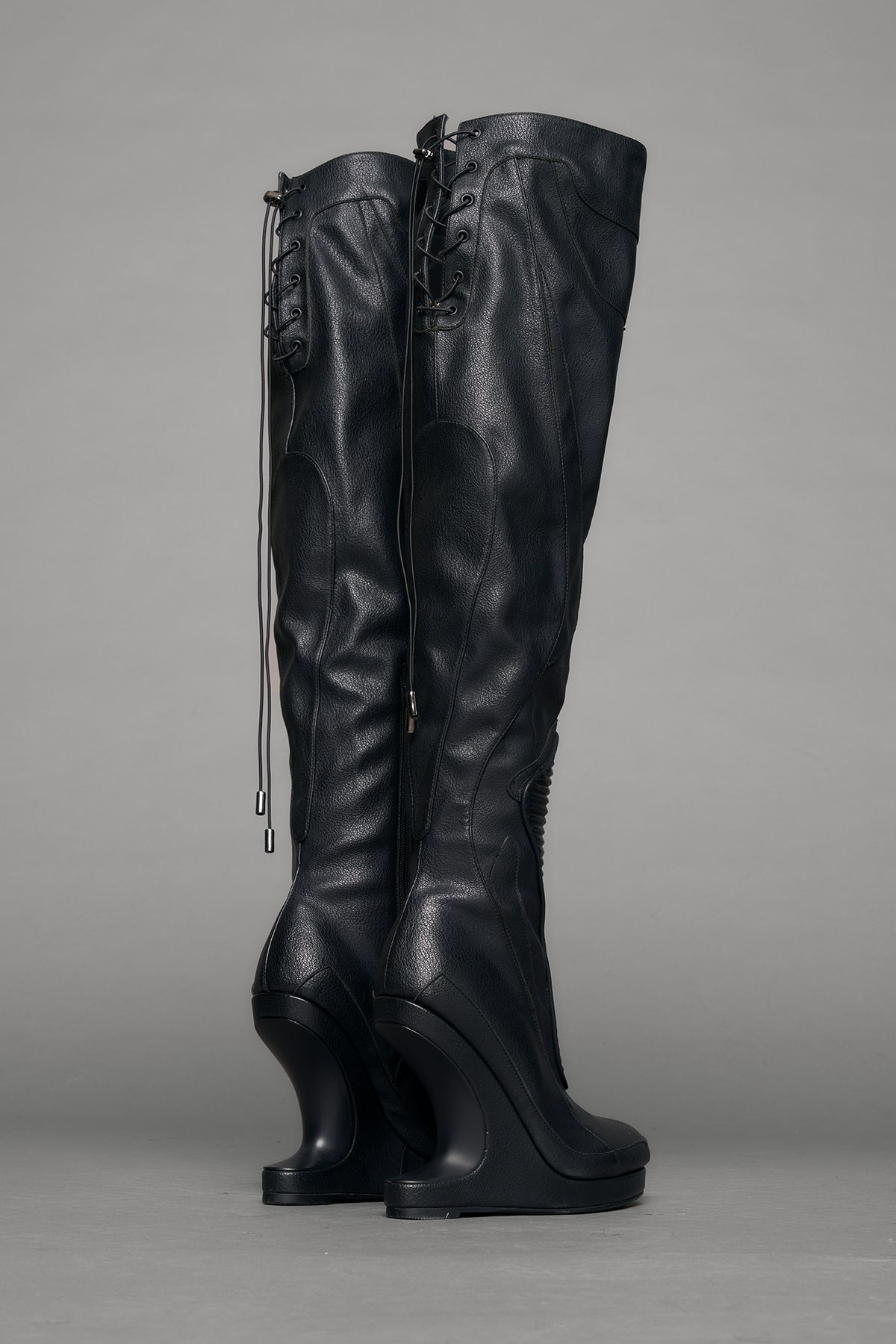 Black leather wedge boot on a gray background