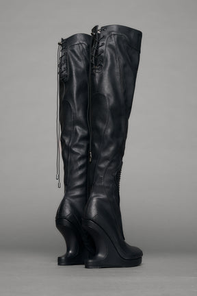 Black leather wedge boot on a gray background