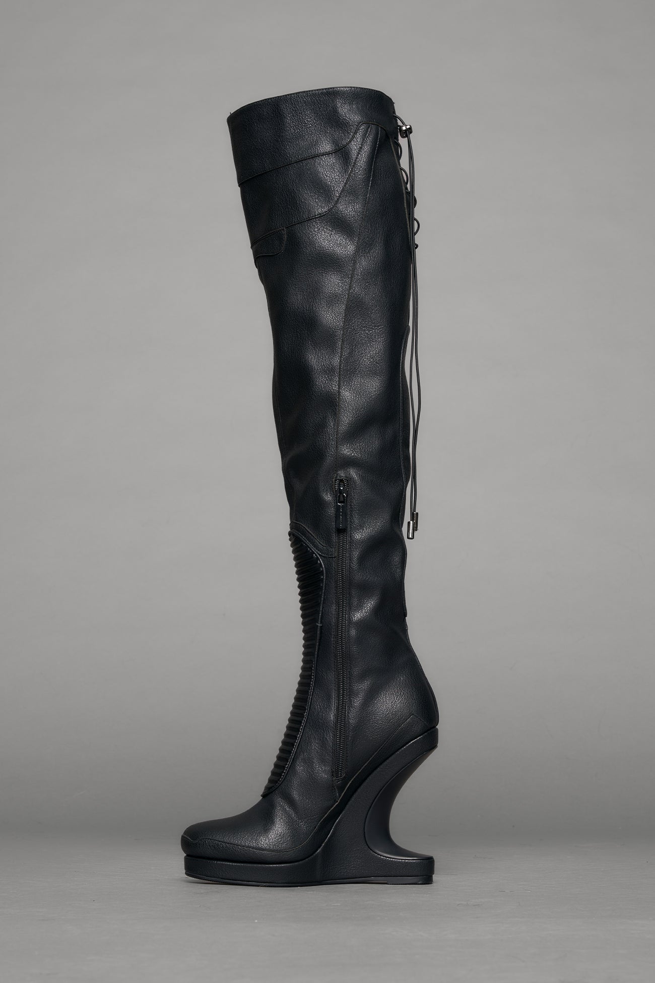 Black leather wedge boot on a gray background