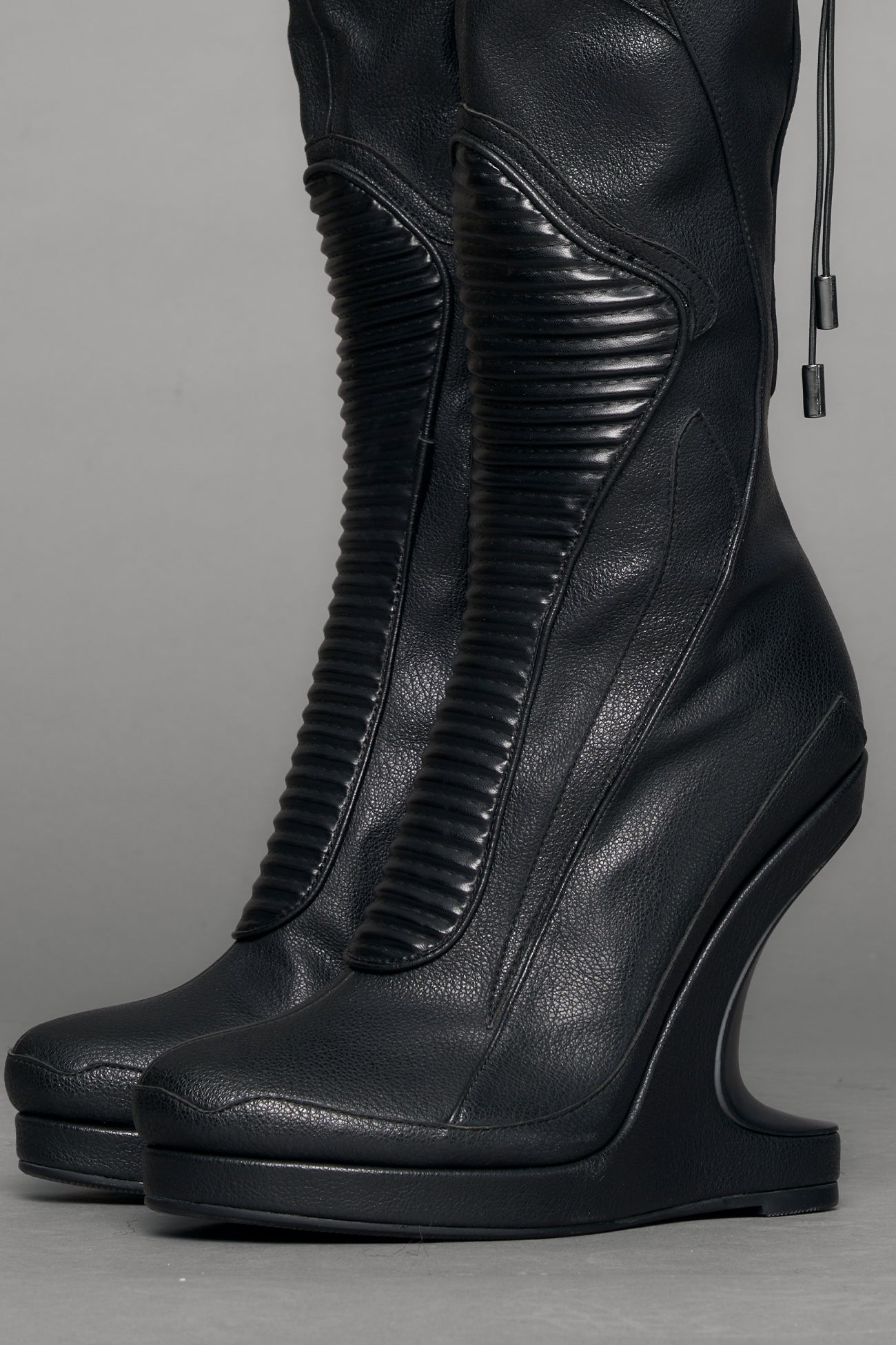 Black leather wedge boot on a gray background
