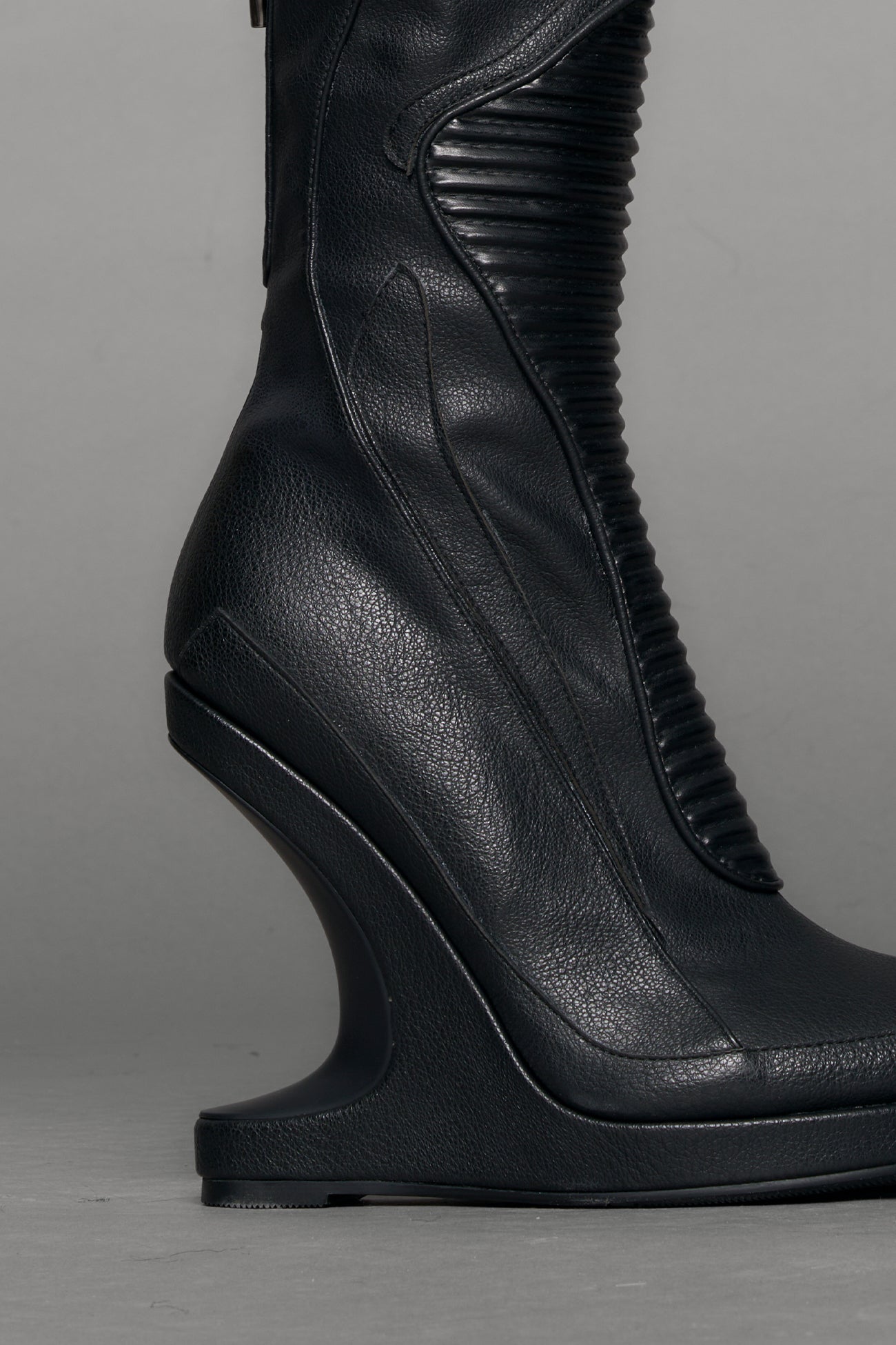 Black leather wedge boot on a gray background