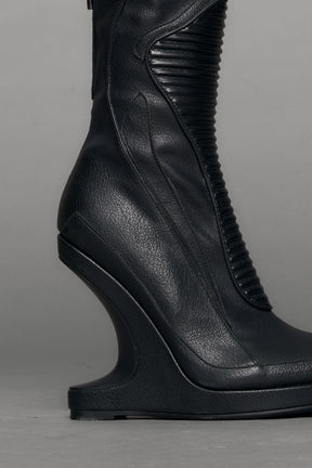 Black leather wedge boot on a gray background
