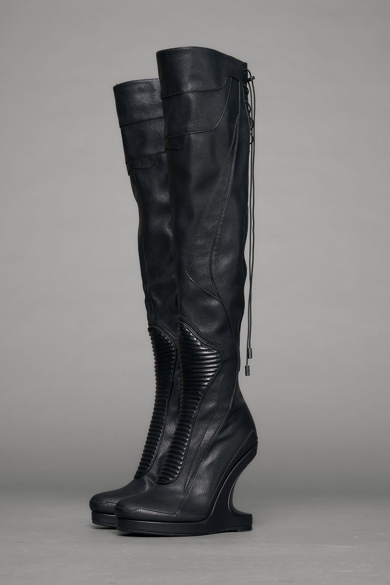 Black leather wedge boot on a gray background
