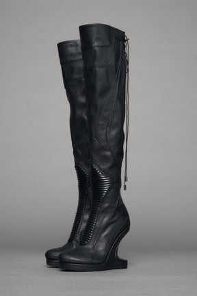 Black leather wedge boot on a gray background