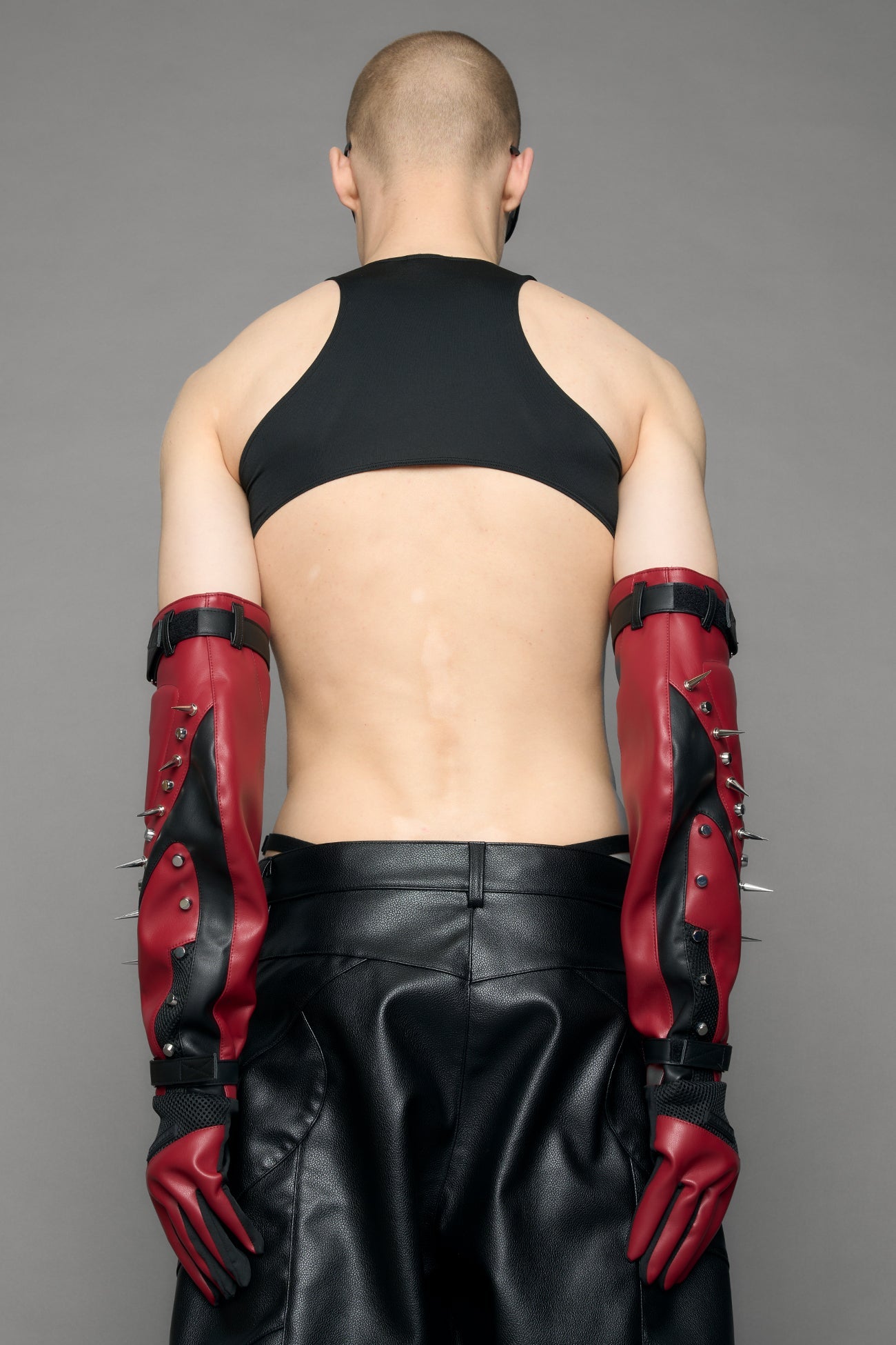 Model wearing a red studded leather gloves with silver and black details